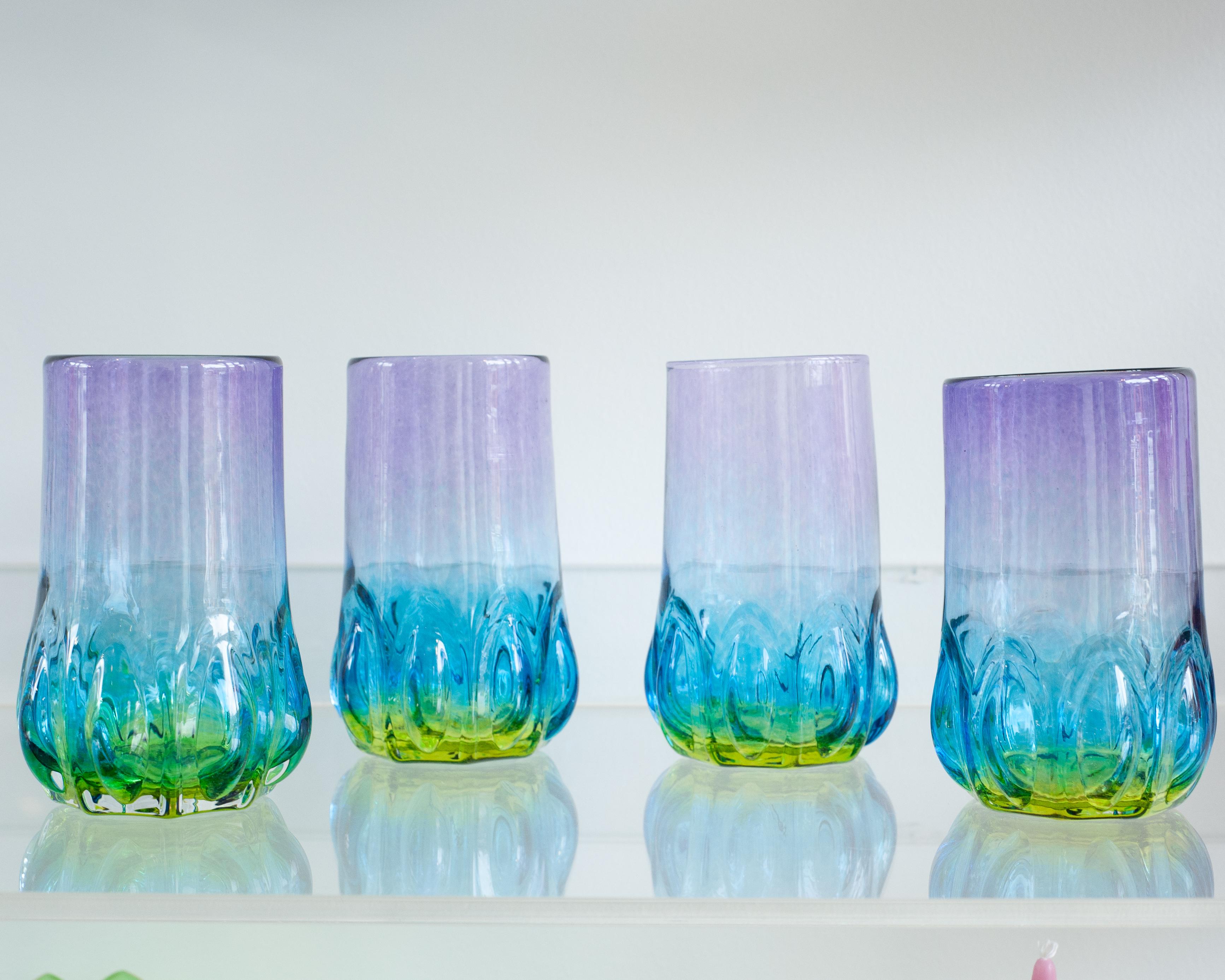 Une célébration de la couleur en mouvement - Ces verres multicolores nouvellement fabriqués, soufflés à la main, brillent d'un dégradé continu de violet, de bleu et de vert. Chaque pièce est formée individuellement, capturant la fluidité du verre en