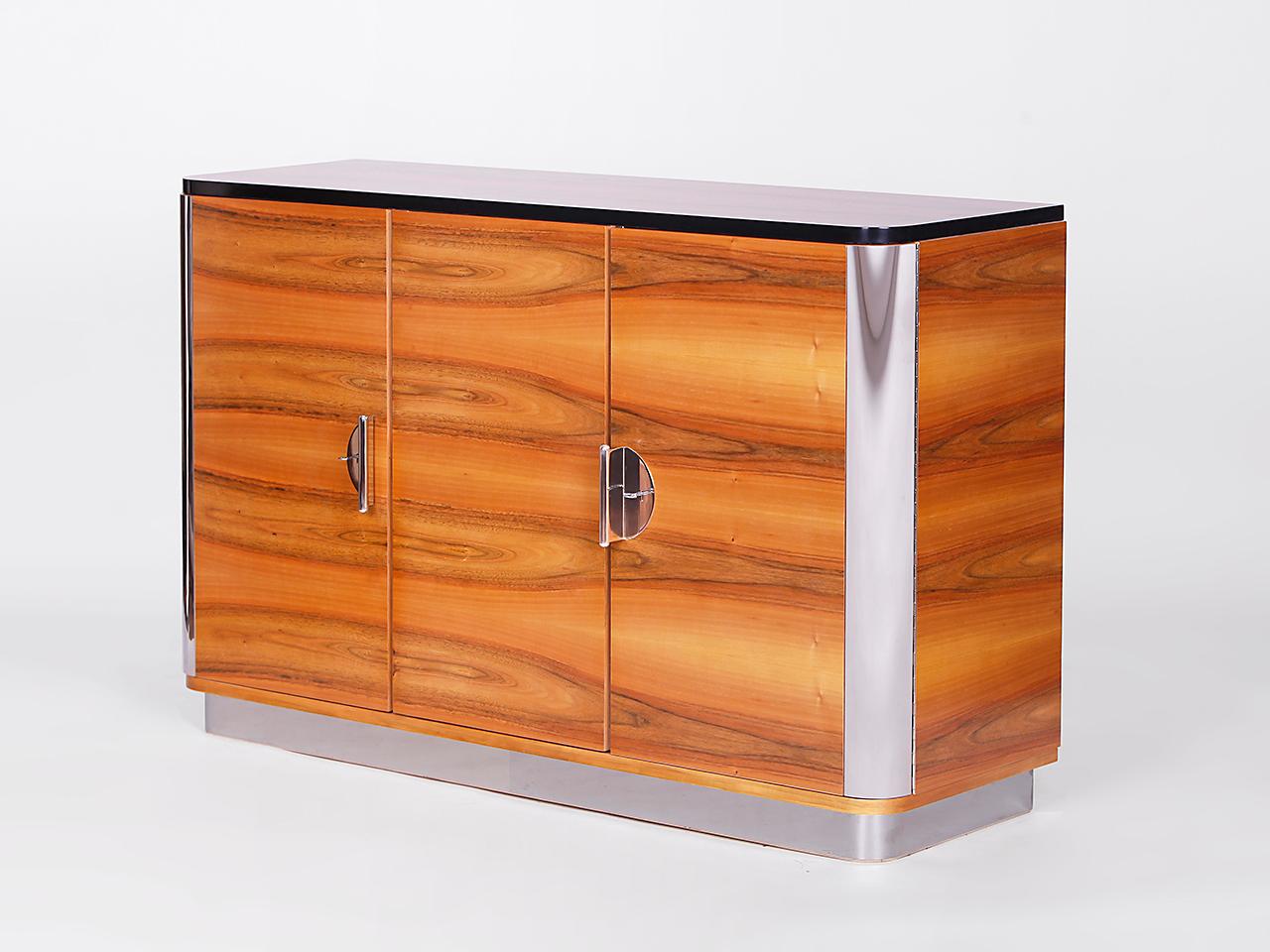 This sideboard was produced by Tschechisches Wohndesign Manufaktur in the style of Czech Functionalism of the 1920s/30s. The surface is veneered with a unique light walnut, the metal applications are made of polished stainless steel. You like the