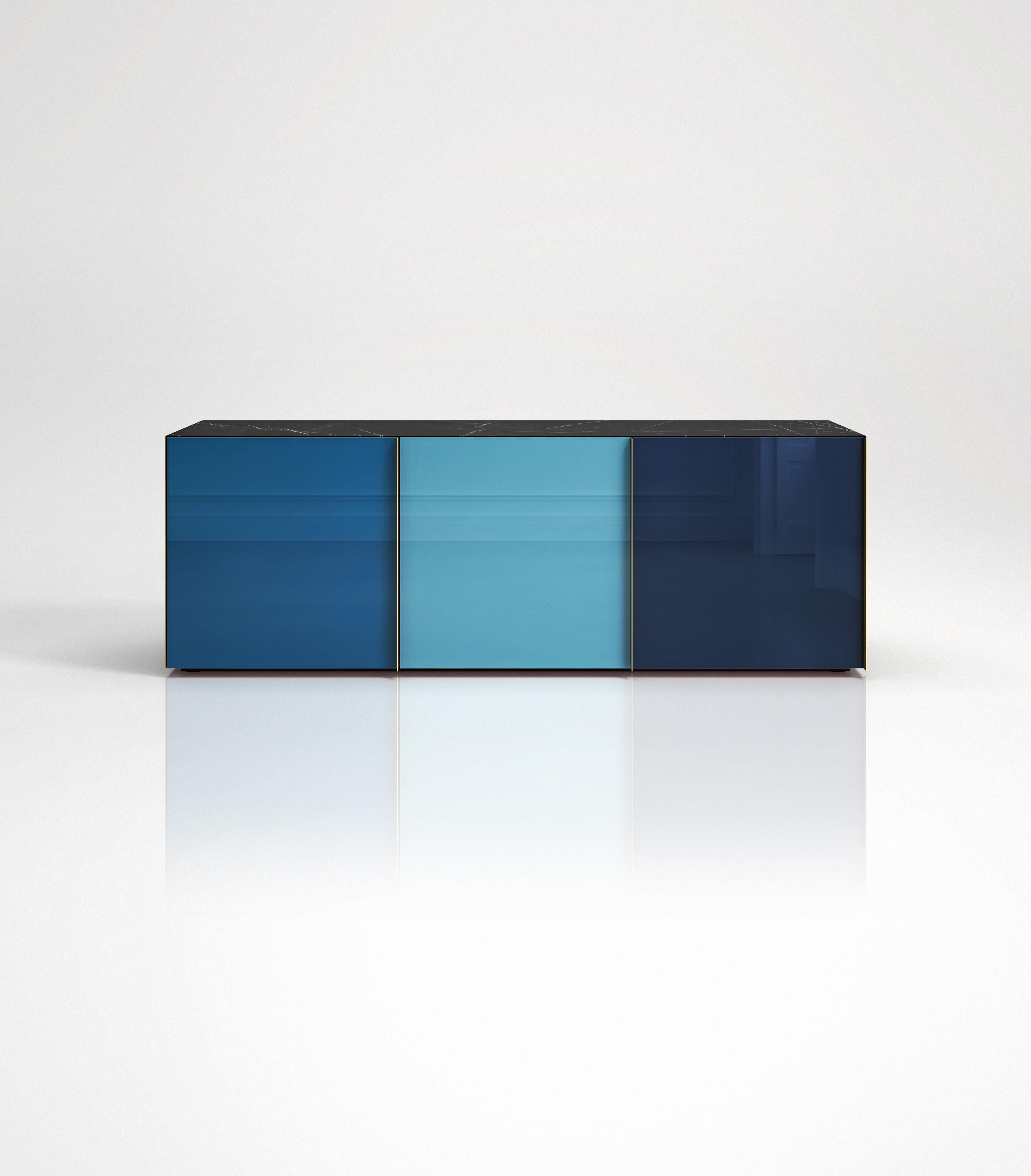 Sideboard 01
Sideboard featuring 3 back-painted glass doors colored in blue tones, New Saint Laurent marble top, lacquered wooden interior and brass handles and side panels. Each of the three compartments has an internal glass shelf. It can be