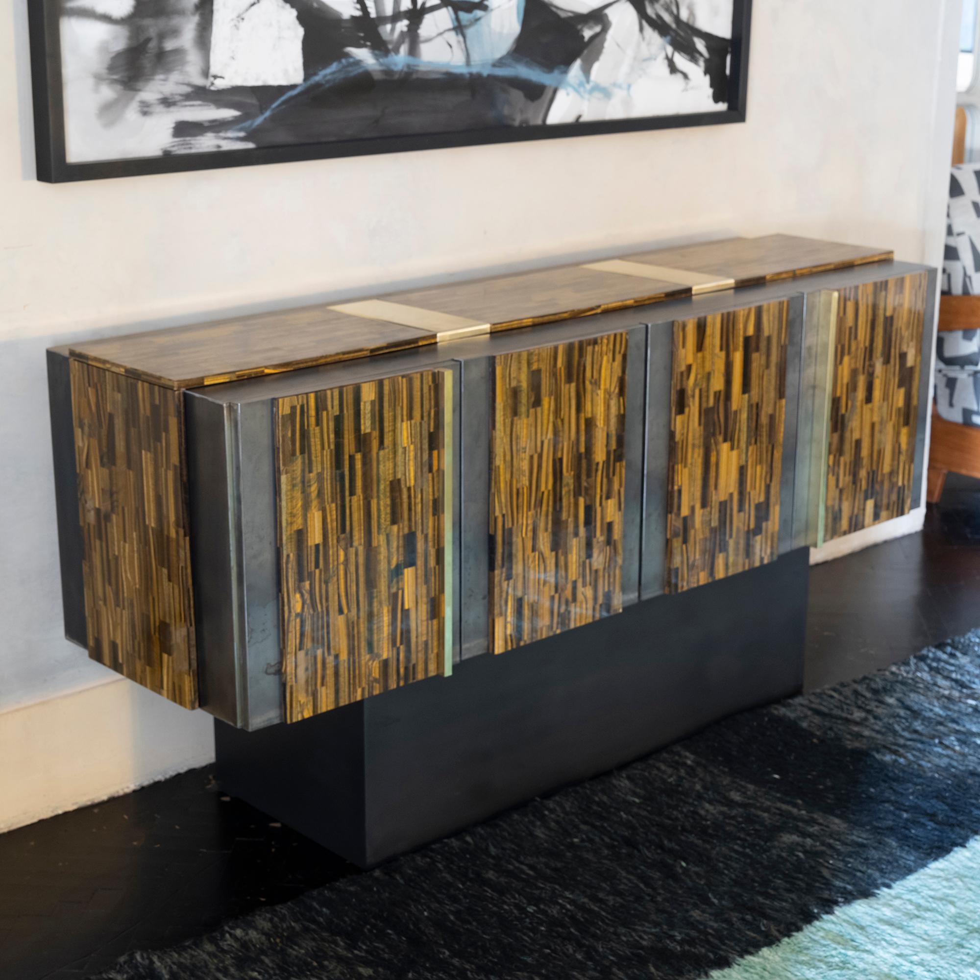One of a kind sculptural sideboard realized by local workshop/artisans in solid wood covered all over in natural brut steel foil and decorative Golden Tiger Eye stone panels with natural brass details, interior lined in grey textured wood veneer and