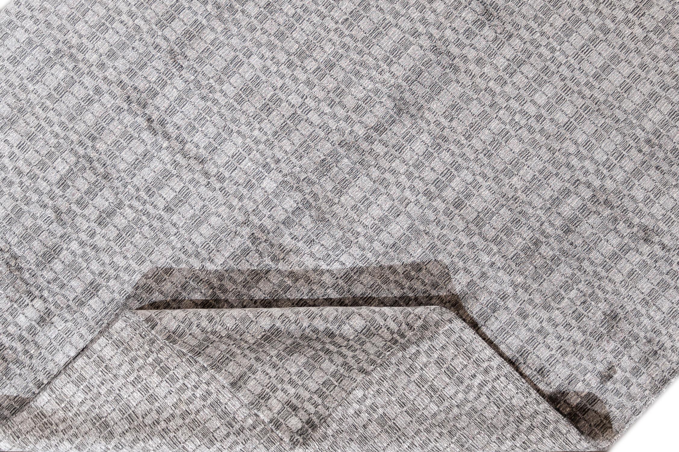 Ein moderner indischer Teppich mit silbernem, geometrischem Allover-Muster und subtilen Andeutungen von Burgunderrot. Dieser hochglänzende, handgeknüpfte Seidenteppich misst 8'11