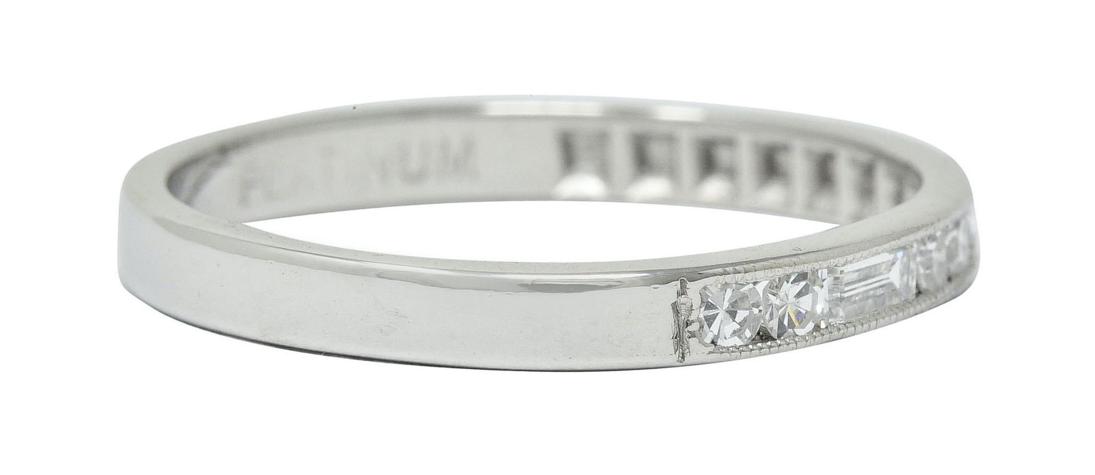 Band ring is channel set to front by single and baguette cut diamonds

Weighing in total approximately 0.22 carat with G/H color and VS clarity

Accented by milgrain edges

Maker's mark and stamped Platinum

Ring Size: 6 1/2 & sizable

Measures: 2.1