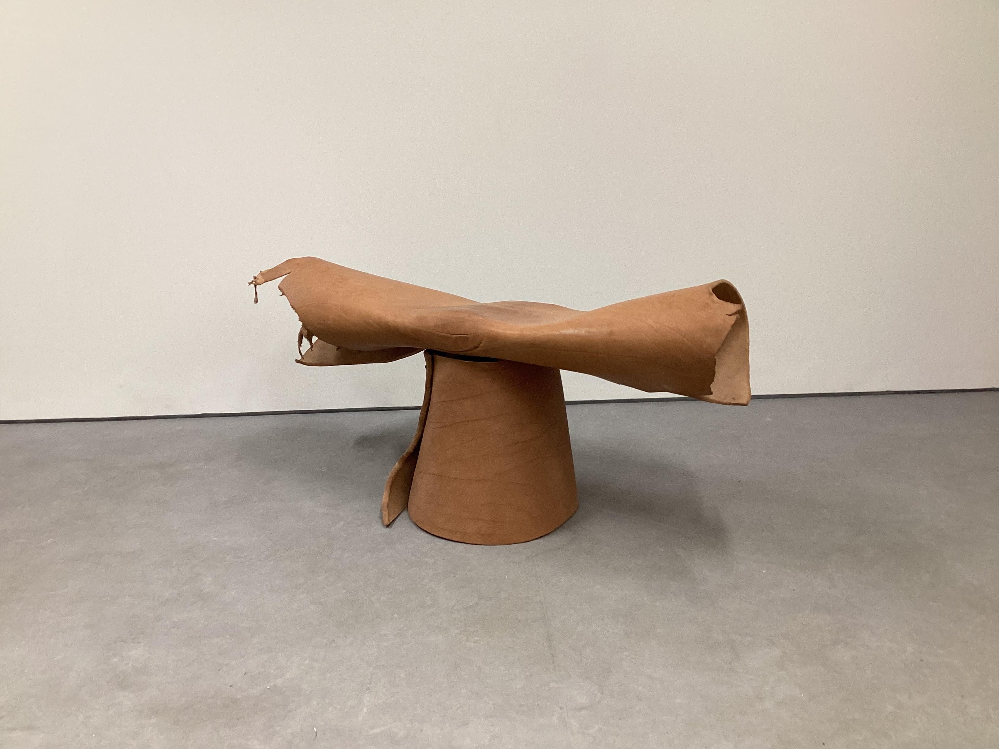 Banc mono-jambe contemporain revêtu de cuir de buffle de Sicile sur une structure interne en bois de pin massif. Fabriqué à la main avec des lignes épurées et minimalistes, il offre une tactilité chaleureuse, une variation de grain naturel et une