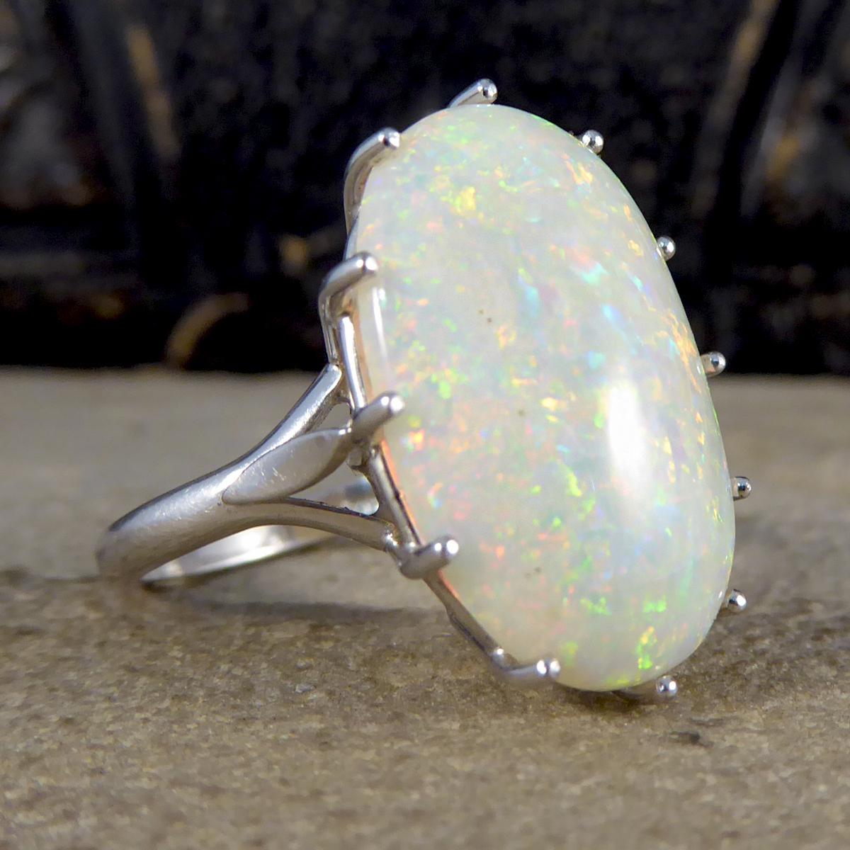 This lovely contemporary ring has been crafted from 18ct White Gold with a single large Opal in a claw setting. The Oval Opal shows a variety of colours glimmering in the light, it accentuates warm oranges and reds in most light with clear blue and