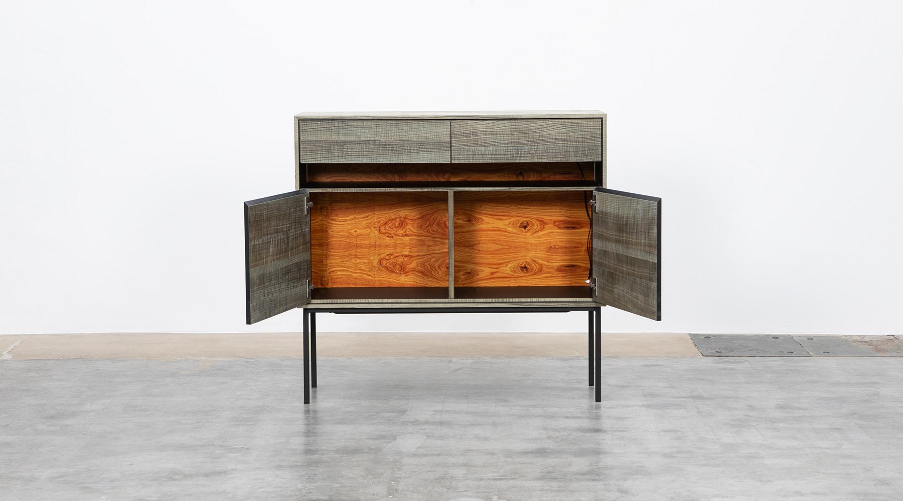 A sideboard made of rough sawn, smoked ash, two doors, two drawers.
The backside is made of rosewood. Manufactured by Atelier Johannes Hock.