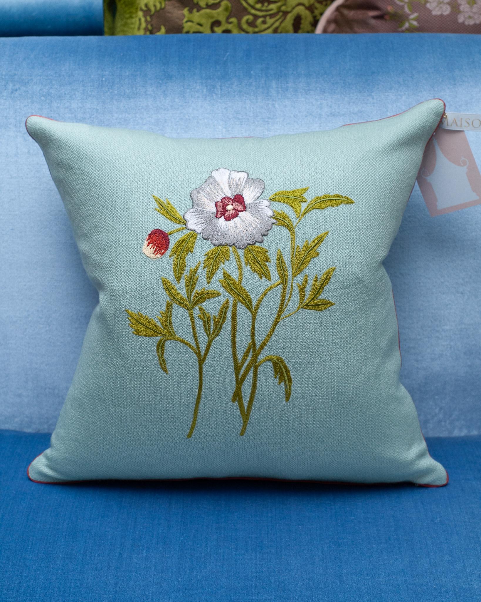 A stunning contemporary soft blue merino wool and linen pillow, trimmed with red piping and embroidered in wool with a single flower motif. Filled with the highest quality Canadian down and feather for a pillow that feels as luxurious as it is