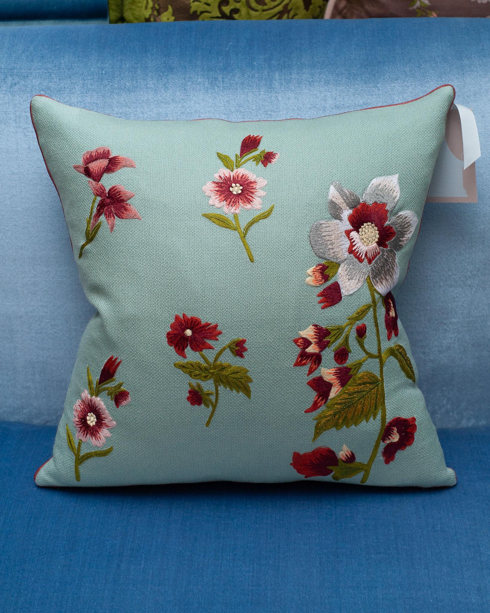A stunning contemporary soft blue merino wool and linen pillow, trimmed with red piping and embroidered in wool with multiple floral motifs. Filled with the highest quality Canadian down and feather for a pillow that feels as luxurious as it is
