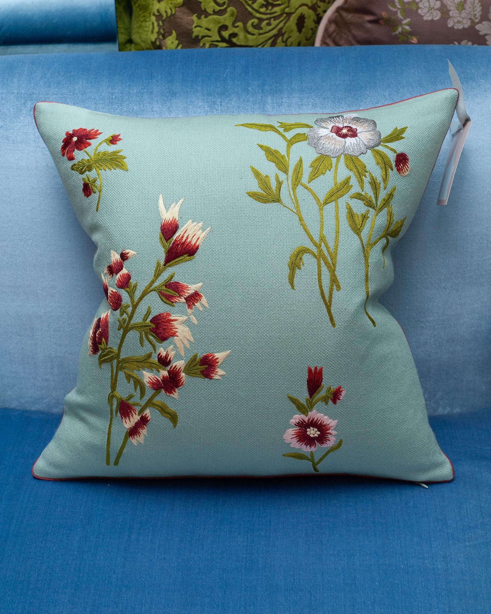 A stunning contemporary soft blue merino wool and linen pillow, trimmed with red piping and embroidered in wool with multiple floral motifs. Filled with the highest quality Canadian down and feather for a pillow that feels as luxurious as it is