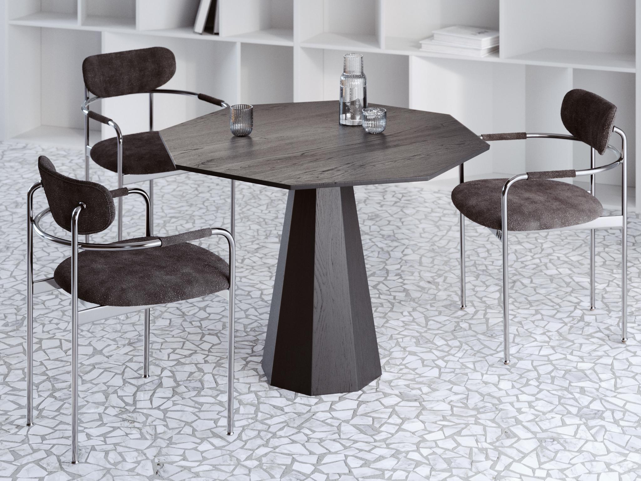 This contemporary dining table is crafted from solid oak and finished in a deep black tone that highlights the natural grain of the wood. Its design is built on bold geometric forms, giving the table a sculptural presence that immediately draws