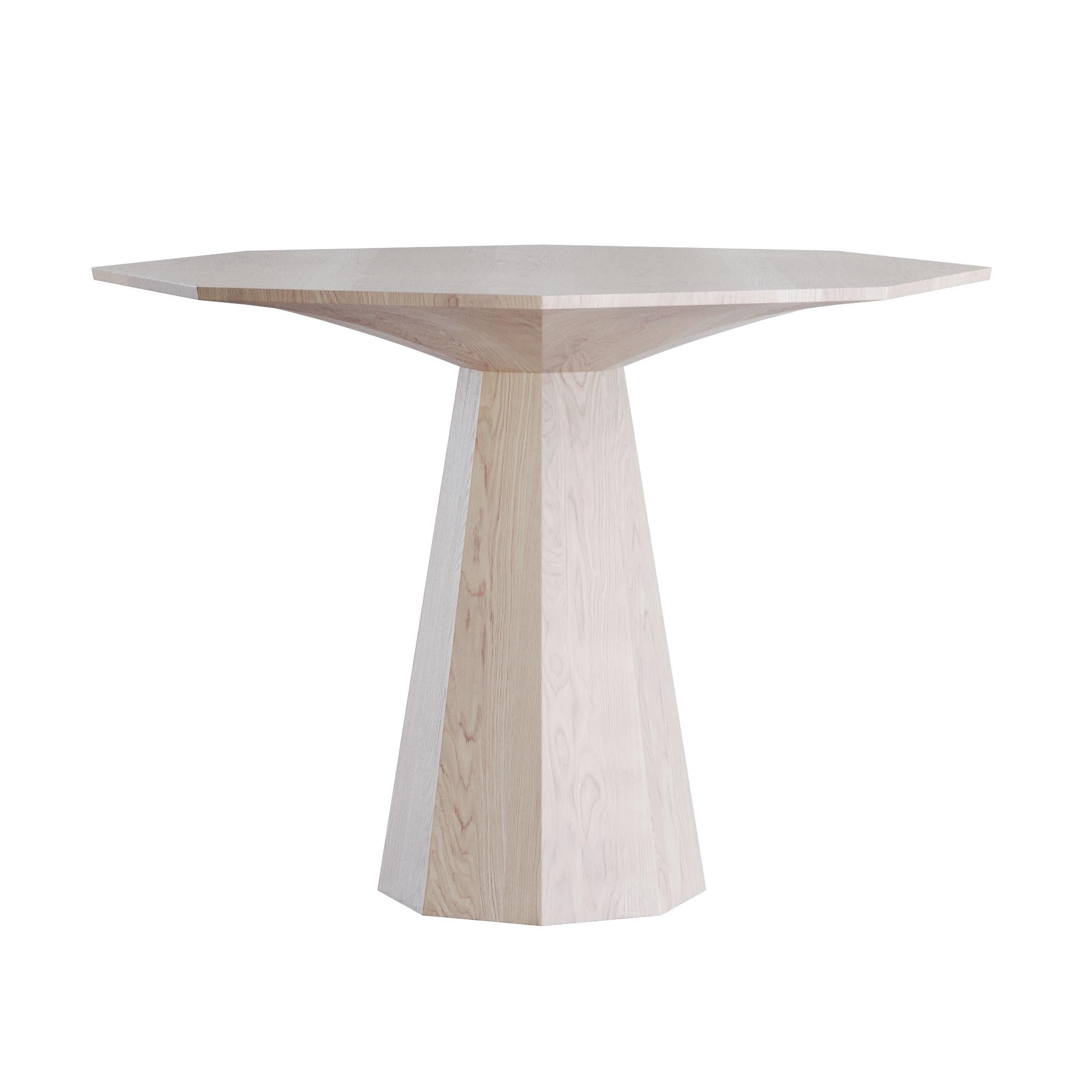 This contemporary dining table is crafted from solid oak with a refined whitewashed finish that softens the natural wood grain and adds a fresh, modern touch. The design is built on bold geometric forms, giving the table a sculptural and distinctive