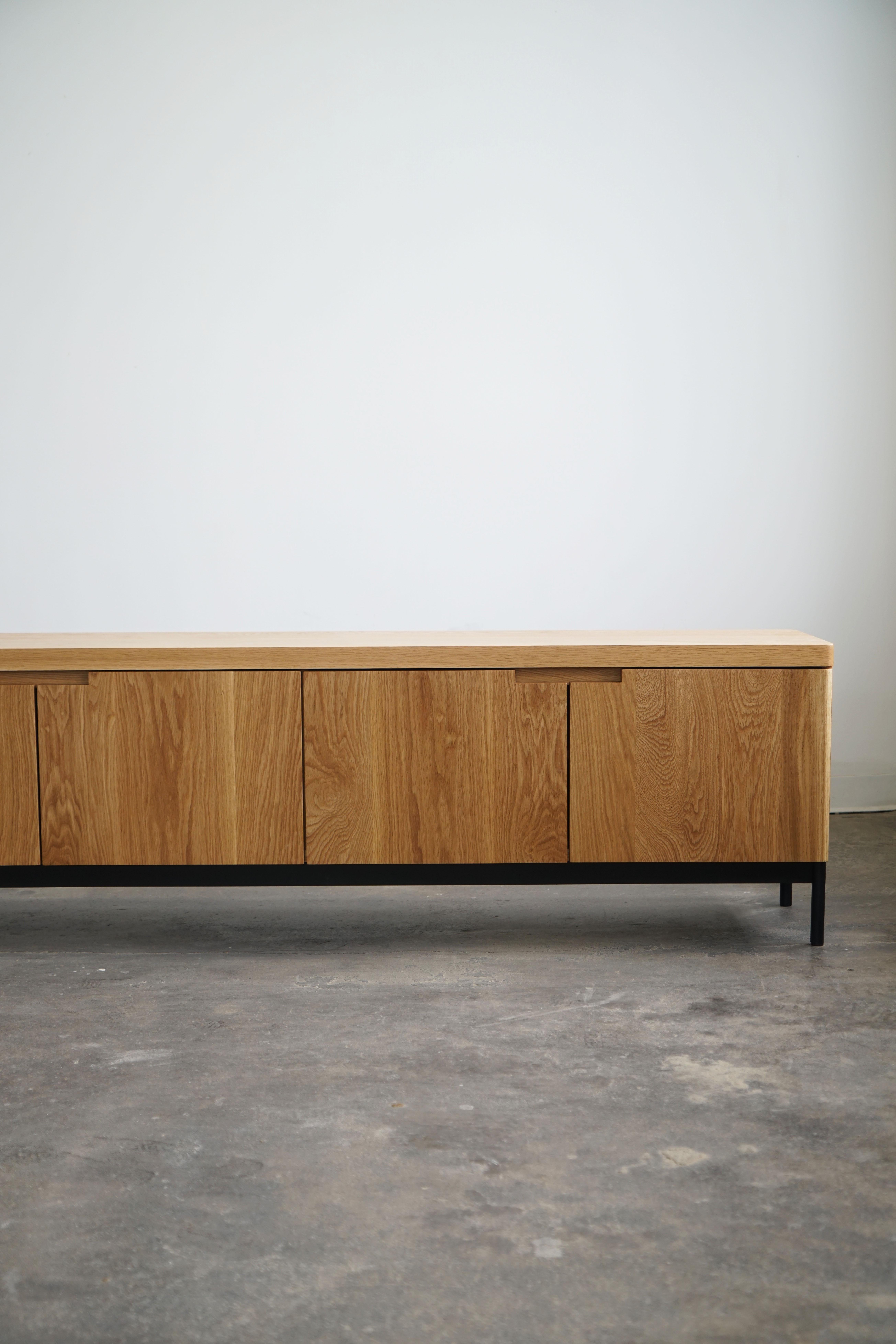 Contemporary solid white oak credenza in a natural finish.
Complete with (6) soft-close doors, adjustable shelves inside, and a steel base. 

Credenza pictured has dimensions of: 120” L x 16” D x 24” H.

This piece is made-to-order, and custom