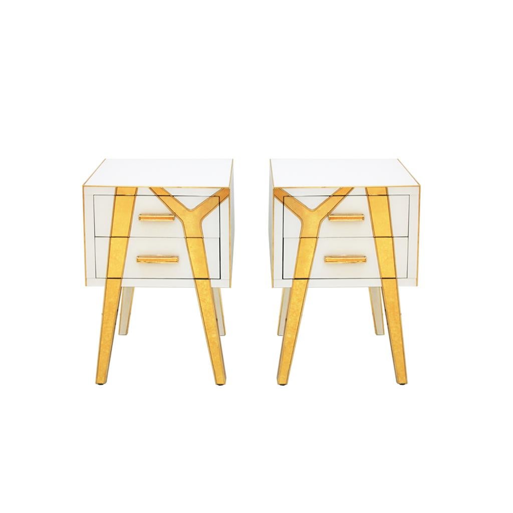 An elegant pair of bedside tables designed and produced by L.A Studio Interiorismo. Structure made of solid wood claded in white and gold glass with brass details. Composed of two drawers and asymmetric legs.
Golden glass color and brass finials