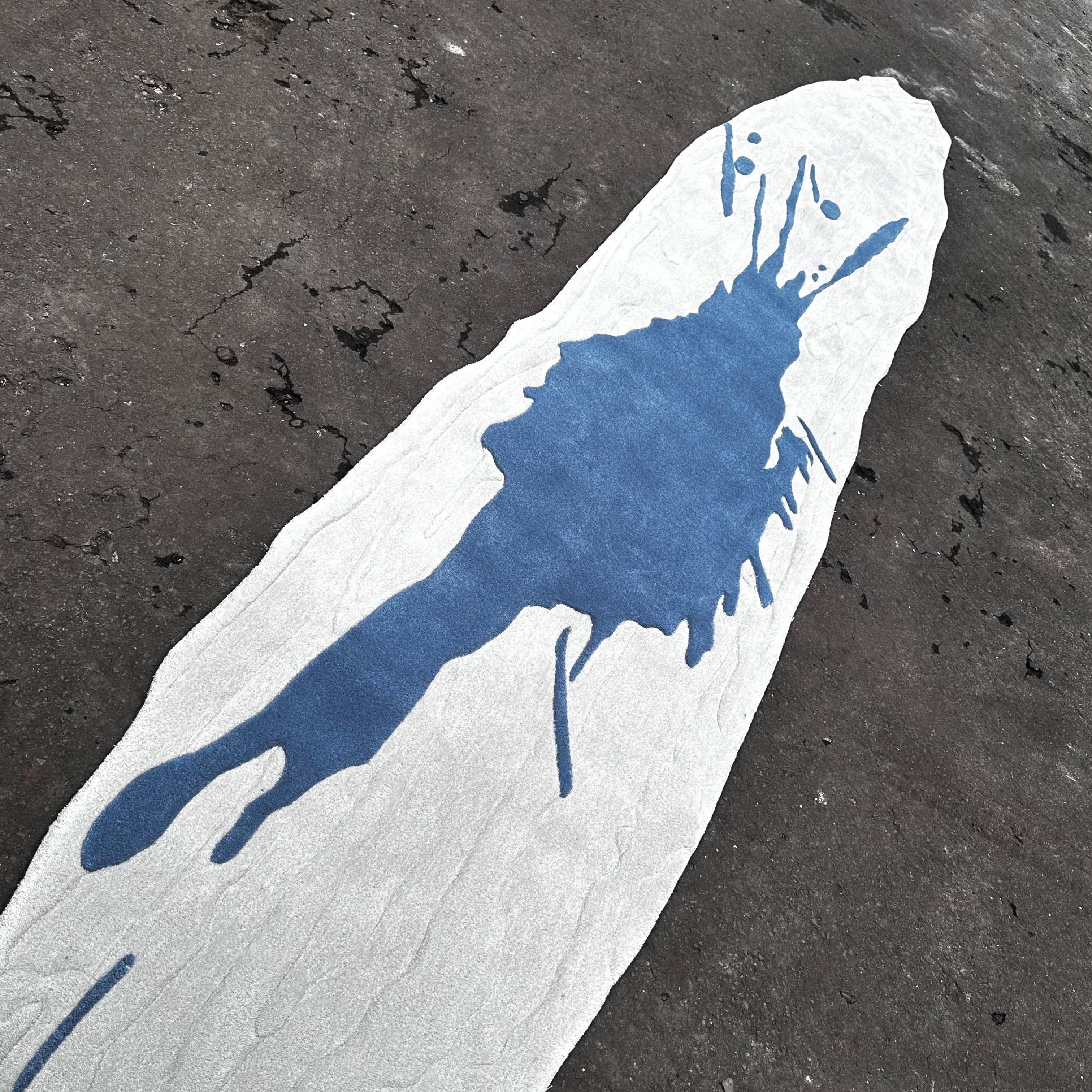 A striking contemporary rug featuring a bold blue splash motif over a soft white ground. Its elongated organic silhouette adds a sculptural quality, making it both a functional rug and a statement art piece.

Hand-tufted in Indonesia from a durable