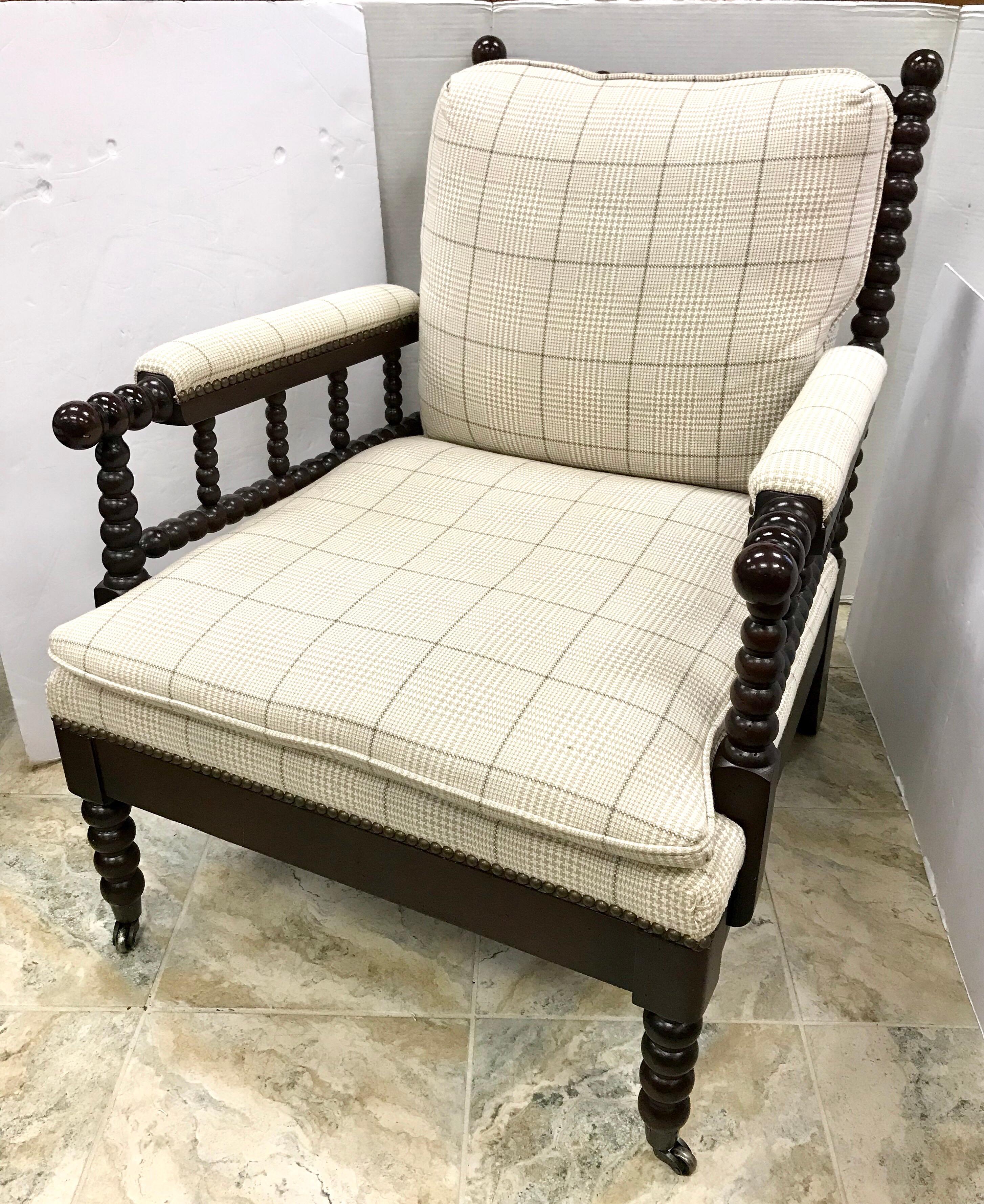 Mahogany spool arm chair by Vanguard, circa 1990s. Upholstered in a neutral plaid and features
casters on front legs and nailheads throughout.