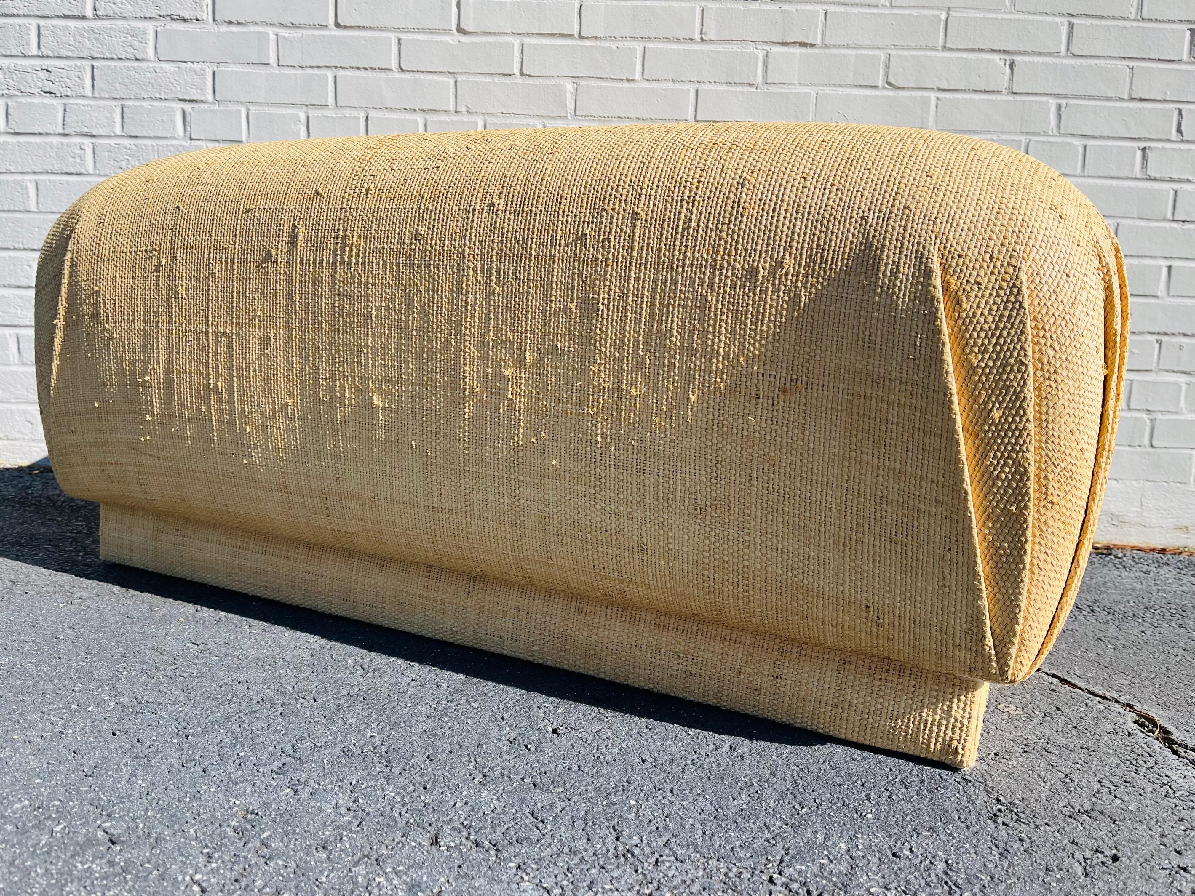 A vintage, late 20th century (possibly early 21st Century) grass cloth upholstered large souffle style pouf or ottoman. This oversized, rectangular footstool can pull double, no make that triple duty, as a place to kick up your feet, a cozy seat or