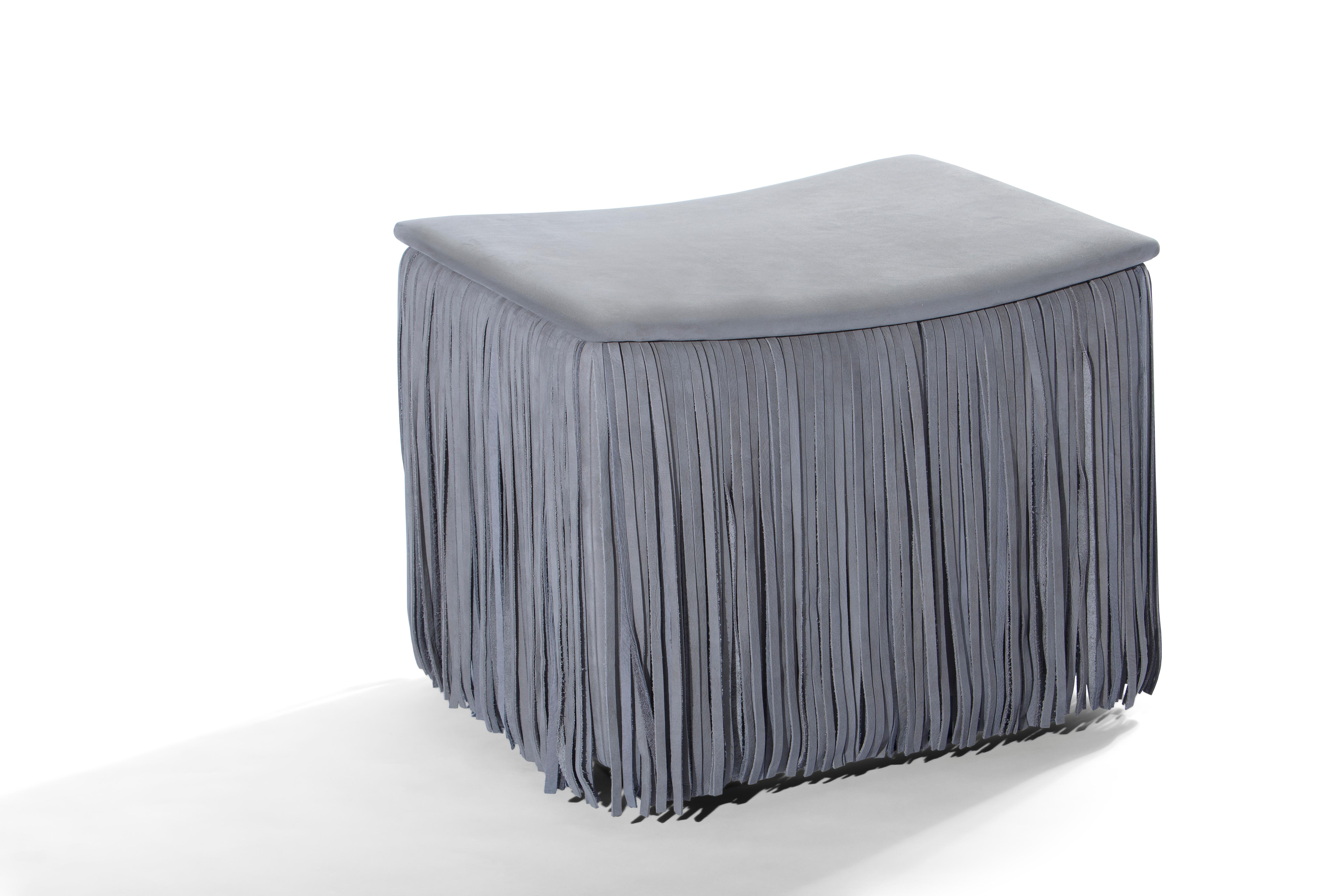Le TAGLIA introduit l'élément de mode intemporel des franges dans le design des meubles de haute qualité. Ce petit pouf carré ludique à l'assise incurvée est entouré d'une jupe dense de franges en cuir Nabuk et apporte à votre espace de vie une