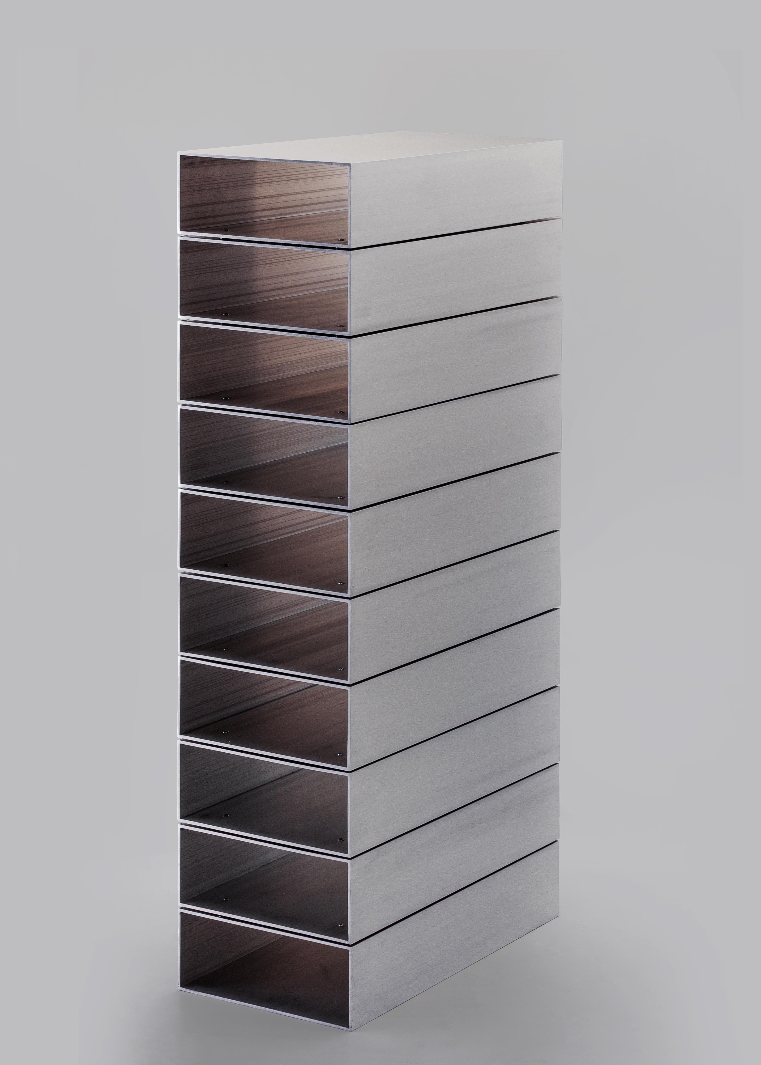 Das Stack-Regal ist ein absolutes Objekt. Die funktionale und skulpturale Form ergibt sich direkt aus den Systemen der Massenproduktion. Das Design basiert auf einem rechteckigen Aluminiumprofil, das in zehn gleiche Teile unterteilt ist. Die