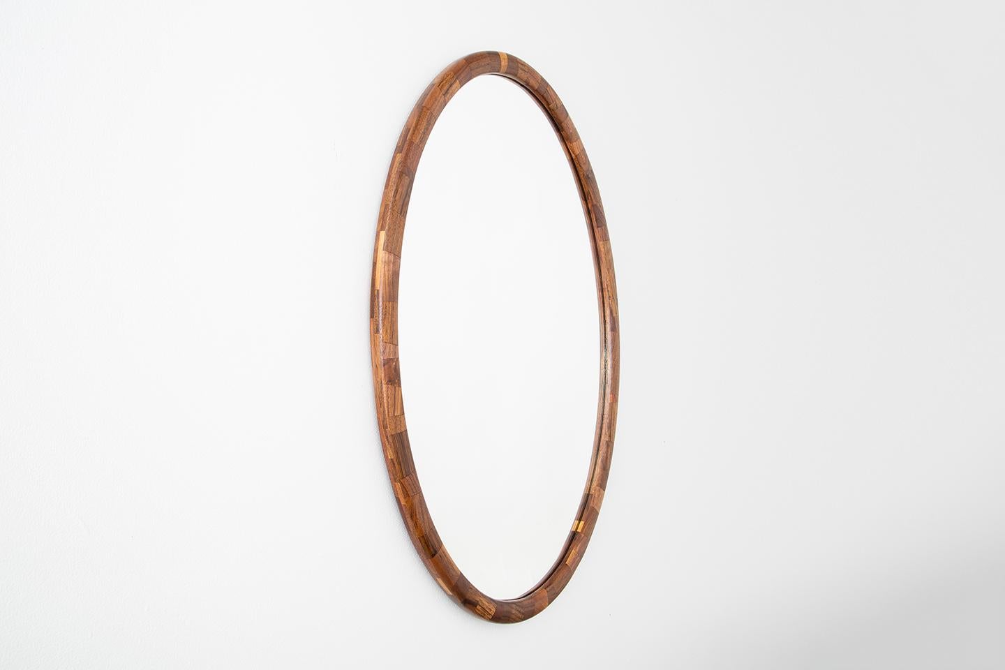 The STACKED mirror's frame has been hand-built. Stacked piece by individual piece, layer upon layer, carefully controlling the profile to create the oval profile. The salvaged wood offers one-of-a-kind patterns made brought to life by Richard’s