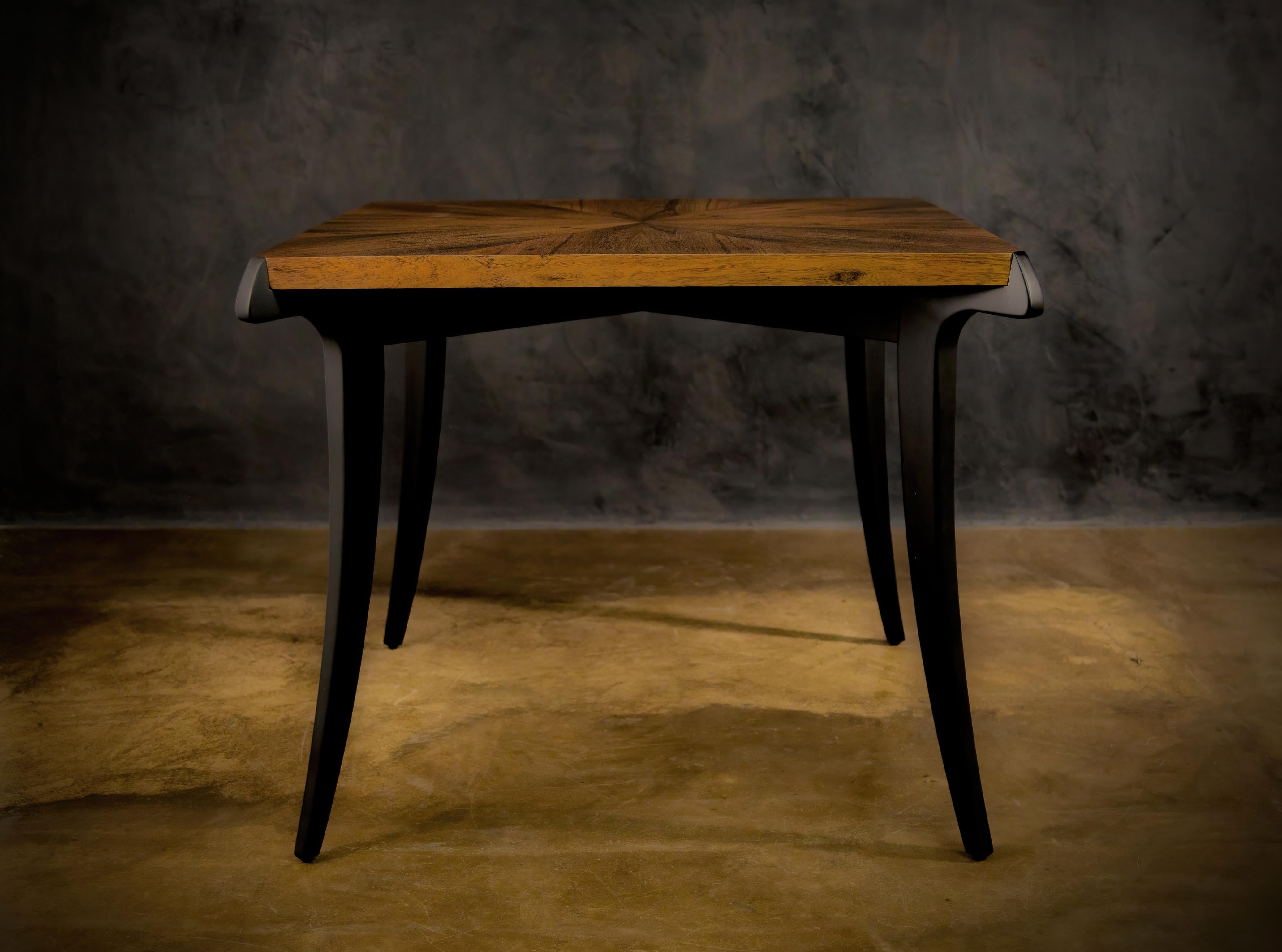 The Uccello writing table or Desk can also function as a game table, or, in larger sizes, as a dining table. Shown here in a naturally finished starburst Argentine Rosewood top with contrasting ebonized solid wood saber legs, evocative of the form