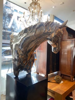 Scultura contemporanea in acciaio di un busto di cavallo su un basamento in marmo