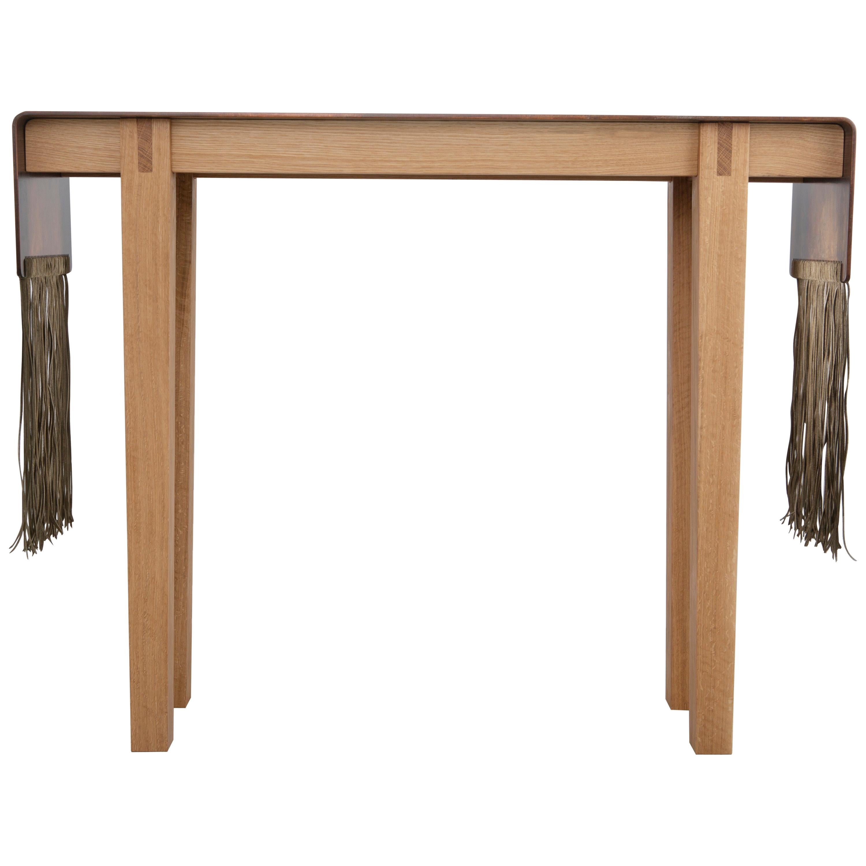 The Native Series was introduced in Design Miami 2020. Inspired by rituals,  grounding and a longing for connection. The console as shown has an aged patina finish on a solid plate of steel draped over the natural oak base with a woven suede lace