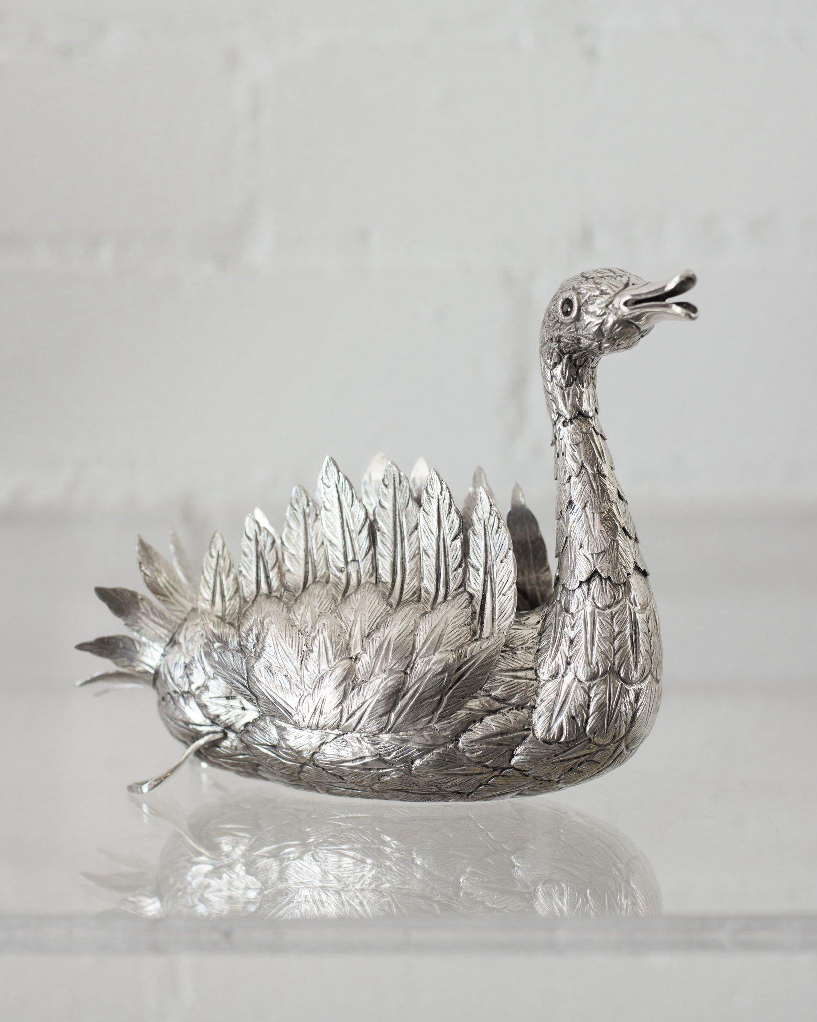 A 925 sterling silver hand chased swan with an articulated neck and wings. Expertly crafted with eyes set with Garnet, made entirely by a master jeweller. Perfect for the table for holding flowers or just as beautiful on its own.