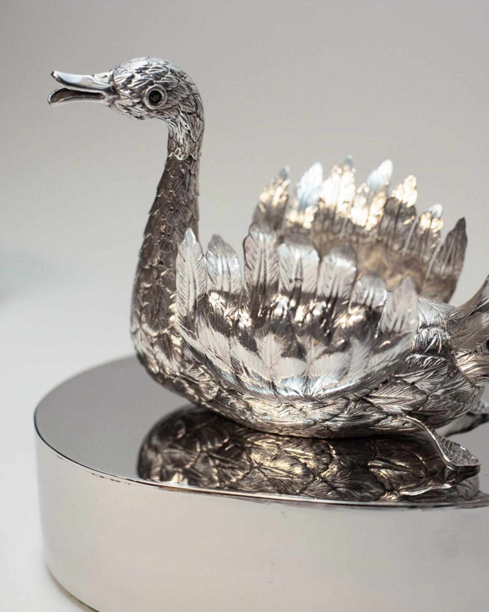 A 925 sterling silver hand chased swan with an articulated neck and wings on a polished nickel display block. Expertly crafted with eyes set with Garnet, made entirely by a master jeweller. Measurements are for swan itself, and base measure 4.5