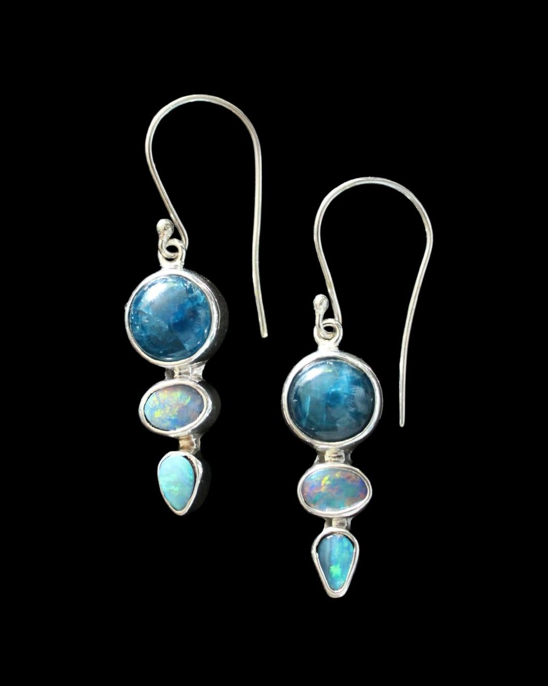 These delightful earrings feature round kyanite cabochons with oval and teardrop Australian opal doublets stones. The light blue iridescent opals compliment the deeper blue of the kyanite. They hang gracefully with French hook sterling silver ear