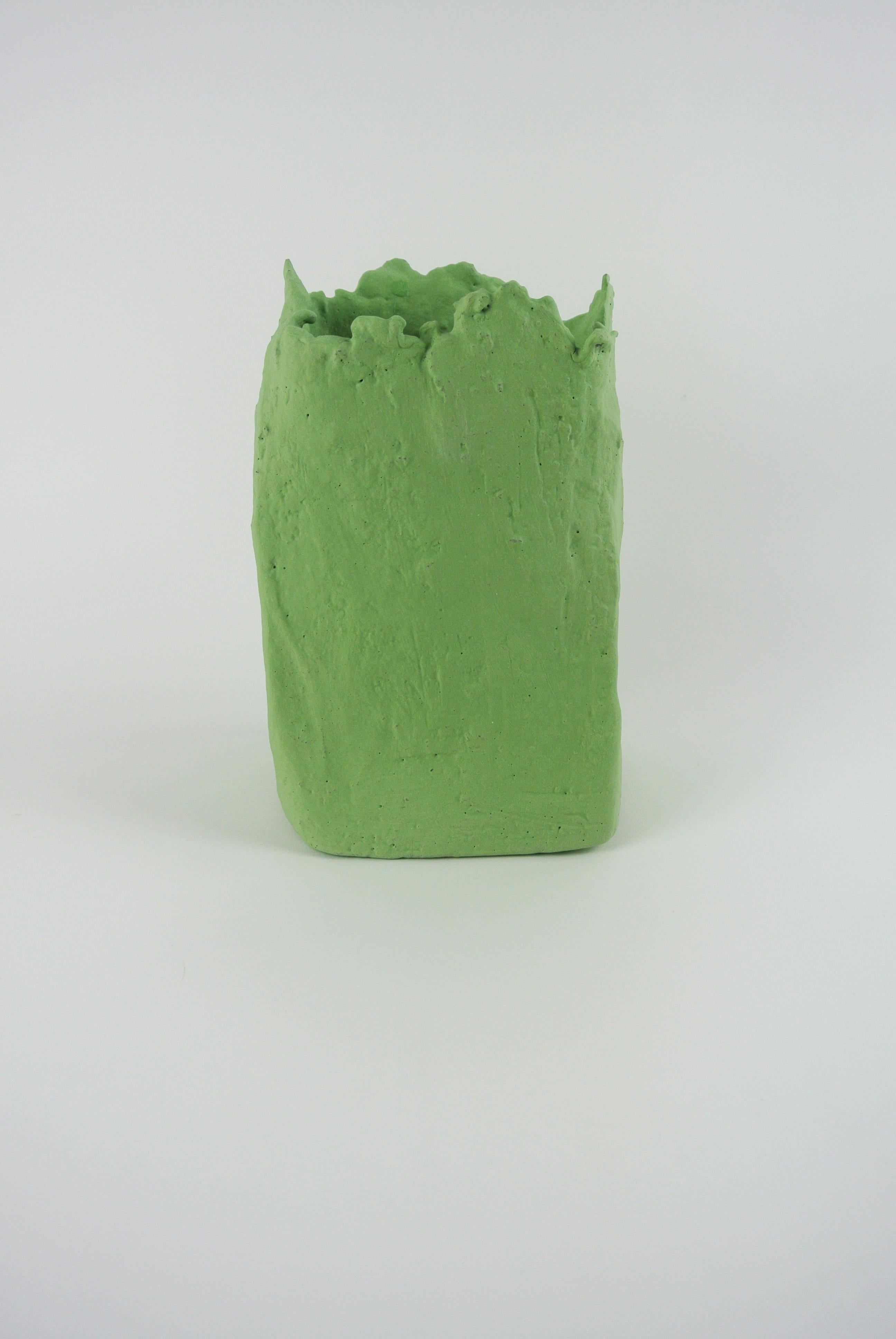 Grey stoneware vessel with matte lichen green engobe on the outside and glossy green glaze on the inside. Asymmetric and has a textured surface. Grey fire sand sporadically visible on the surface. Functional and holds water.