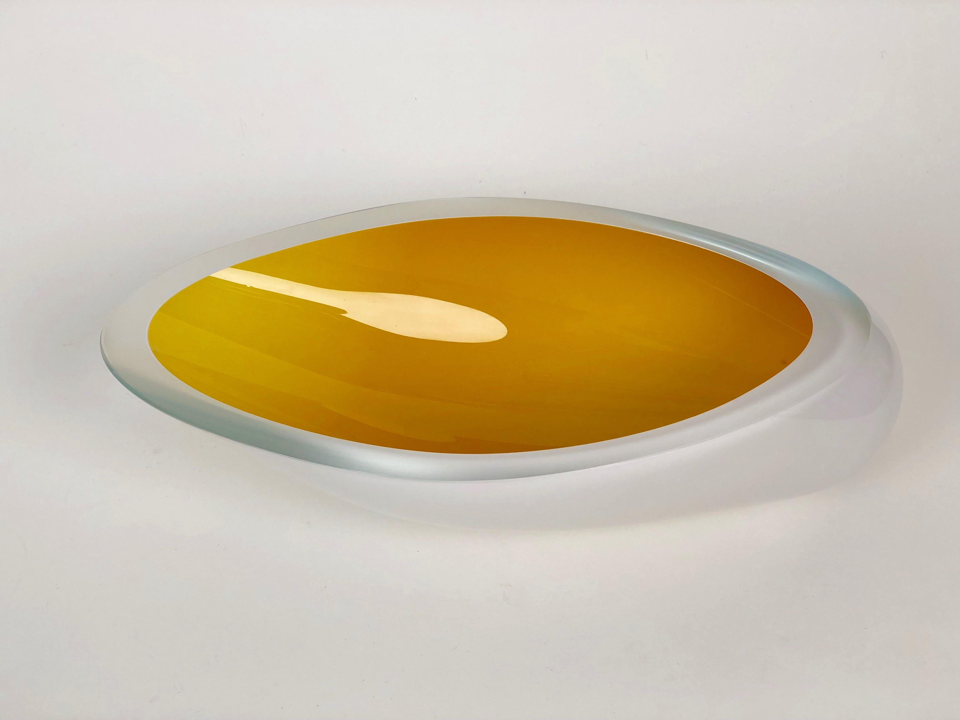 Contemporary studio glass bowl handmade in the Czech Republic. The color is made up of two layers applied to the inside, first white and
then yellow. The body is clear glass and the opening has been ground flat on the wheel. The combination of