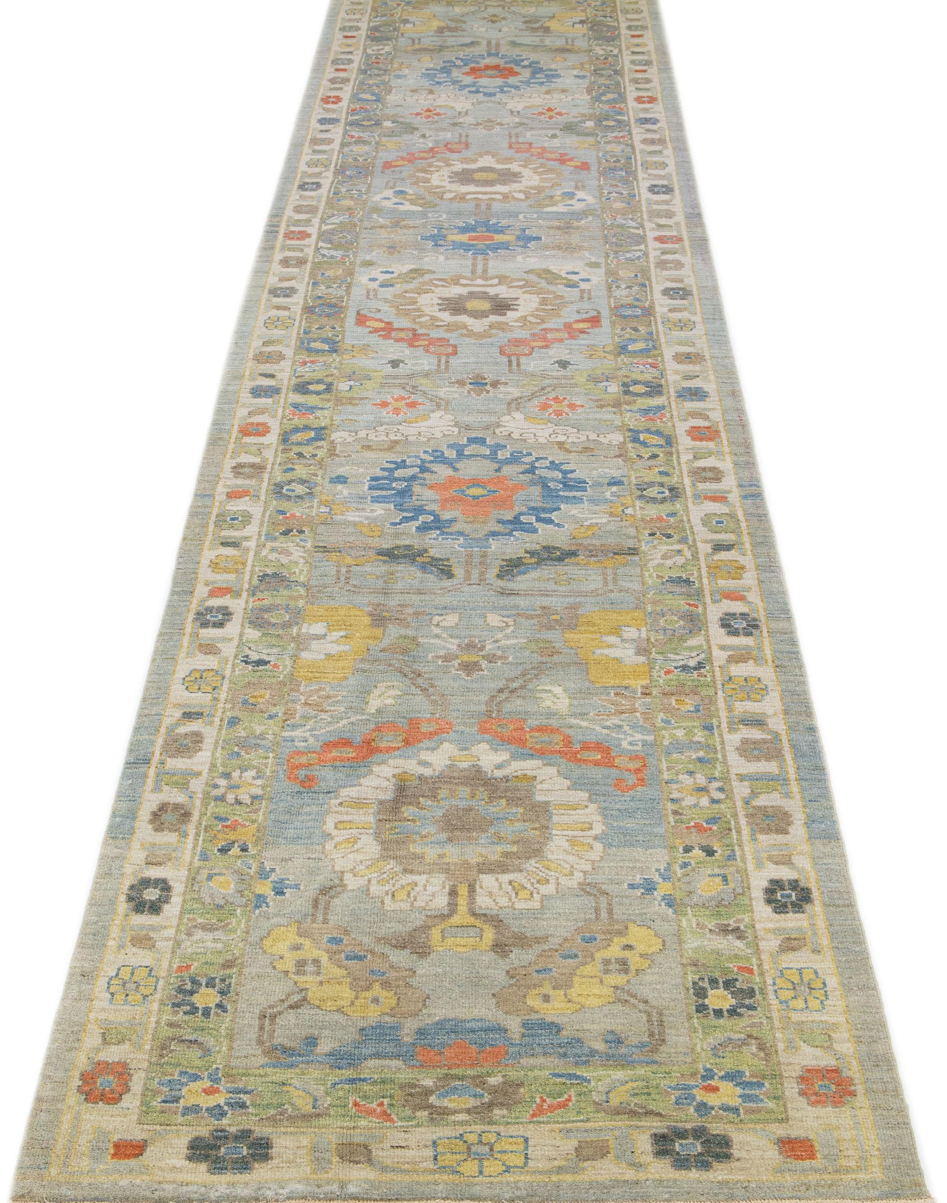 This contemporary take on the traditional Sultanabad style is showcased in an exquisite hand-knotted wool rug with a striking light blue color. An intricately designed beige and green frame accentuates its all-over floral motif, adorned with