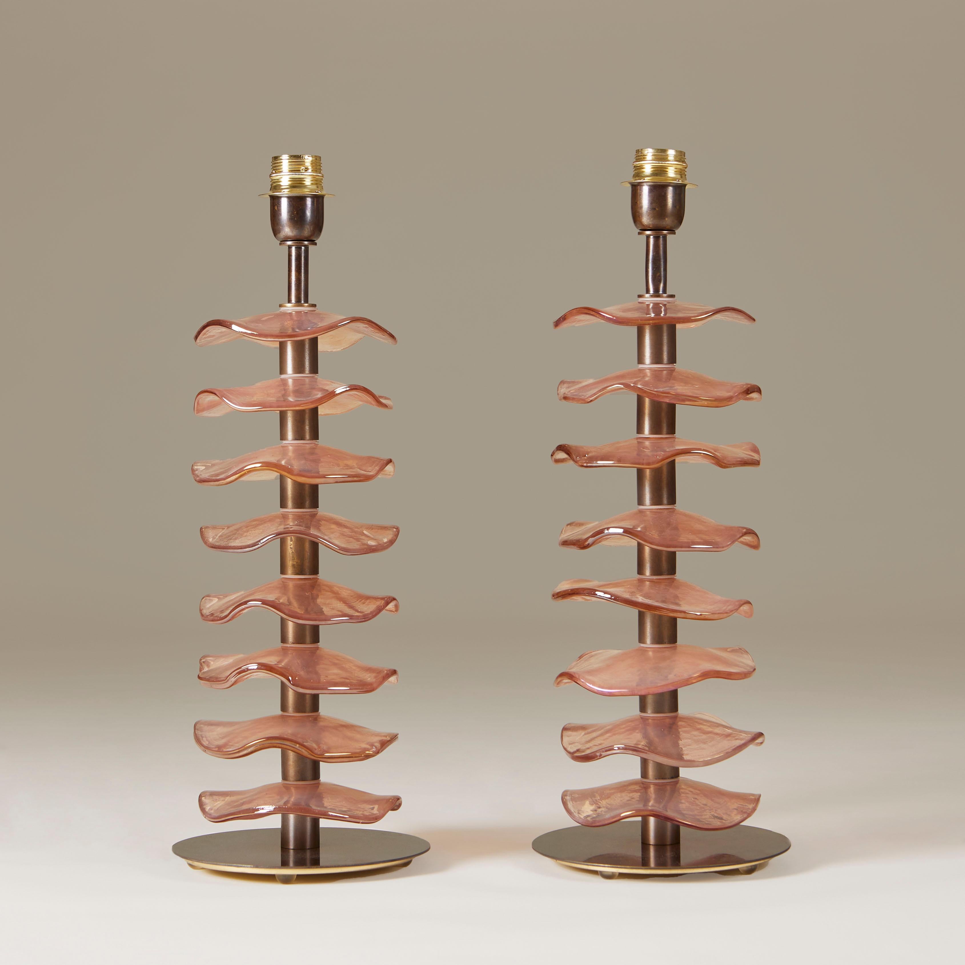 Imposing pair of table lamps consisting of eight individual handmade Murano peach/rose petal disks with subtle iridescent sheen. Each sits on a dark brass stem with simple circular brass base.

Lampshades optional. 70cm high x 35cm diam with shade
