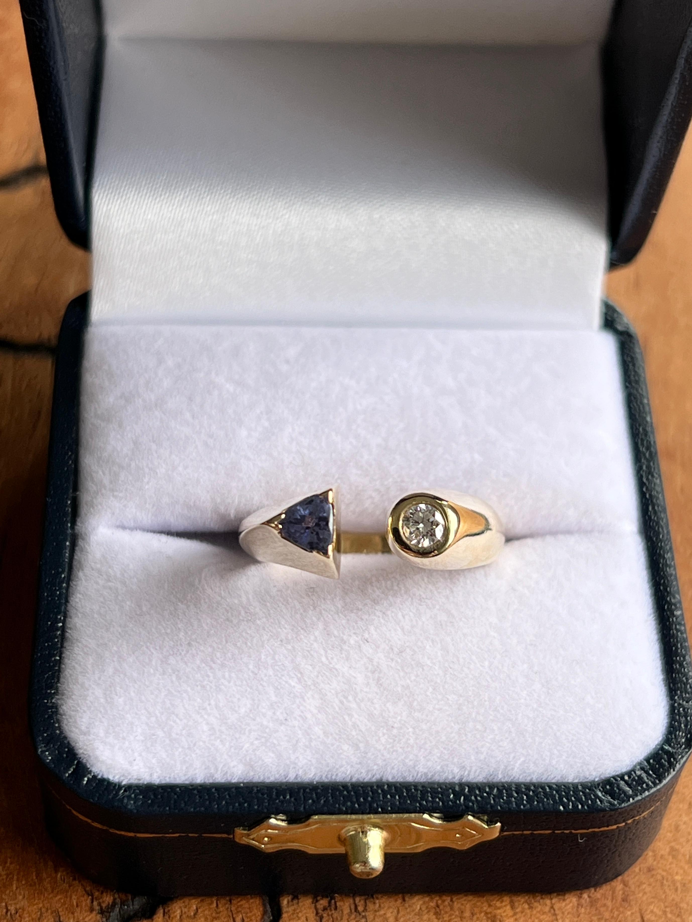 Cette bague ouverte contemporaine en or jaune 14 carats présente une silhouette fraîche et moderne mise en valeur par le contraste saisissant des pierres précieuses. Le design présente une tanzanite de 5 mm de diamètre, taillée en trillion, sertie