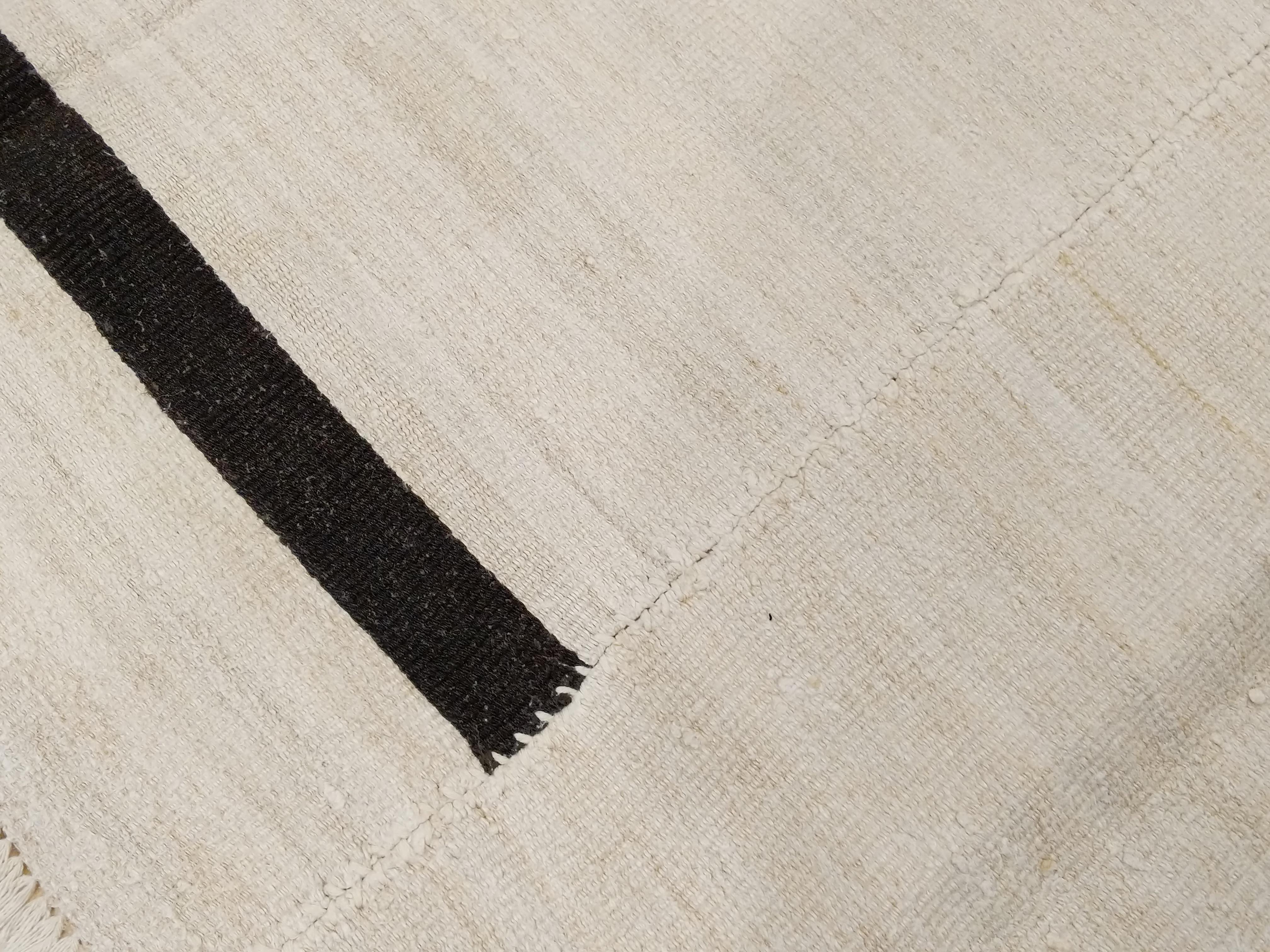 An outstanding modern composition inspired by Minimalist nomadic textile art, this flat-weave is woven entirely in natural hemp, both dyed black as well as in its undyed white color. According to an age-old tradition, these are woven on narrow looms