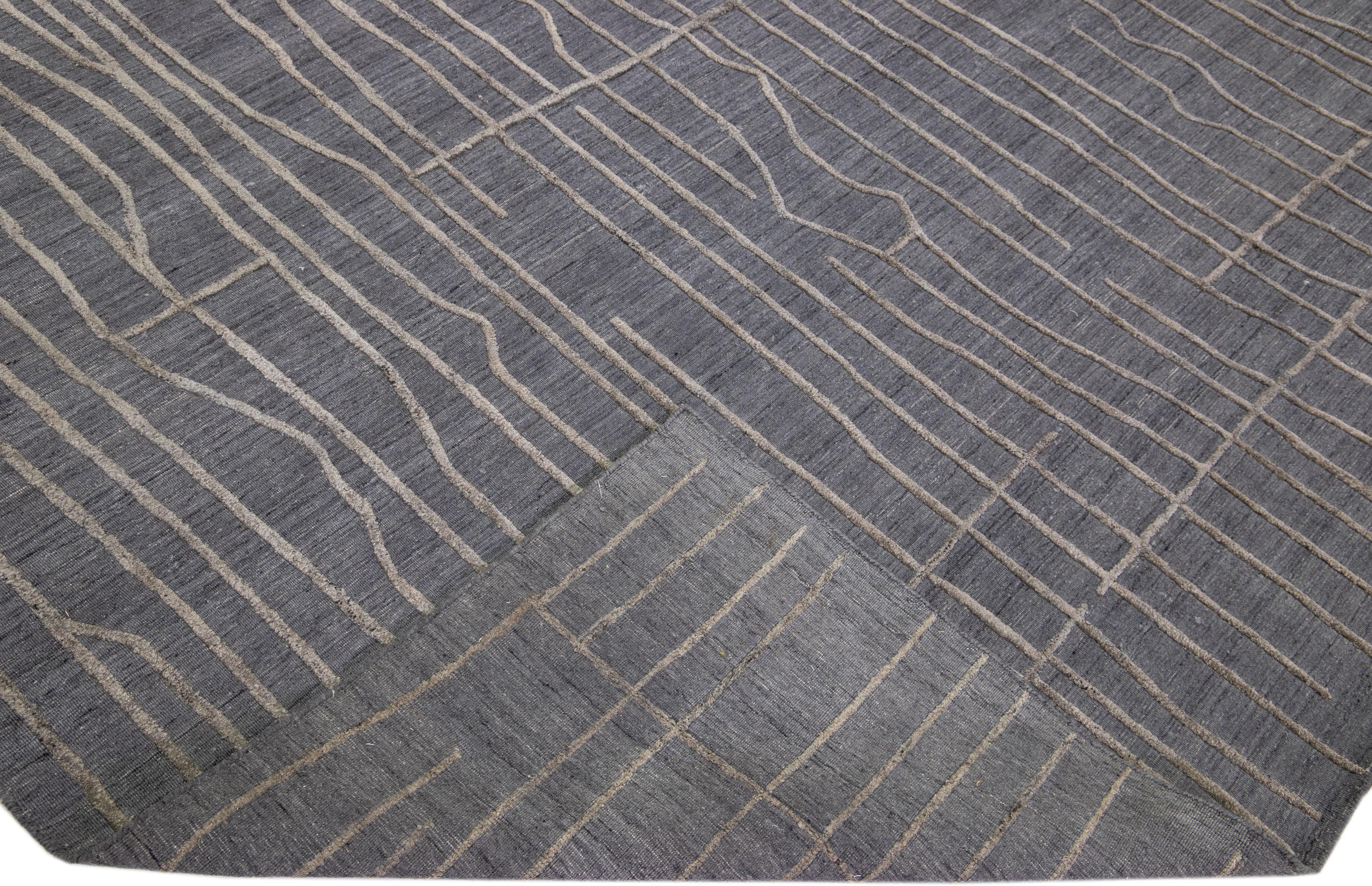 Schöne zeitgenössische Teppiche von Thom Filicia Home Collection. Dieser indische handgewebte Teppich aus Wolle und Viskose hat ein anthrazitfarbenes Feld und graue Akzente im gesamten Design. 
Thom Filicias Auge für exquisite Details und schöne