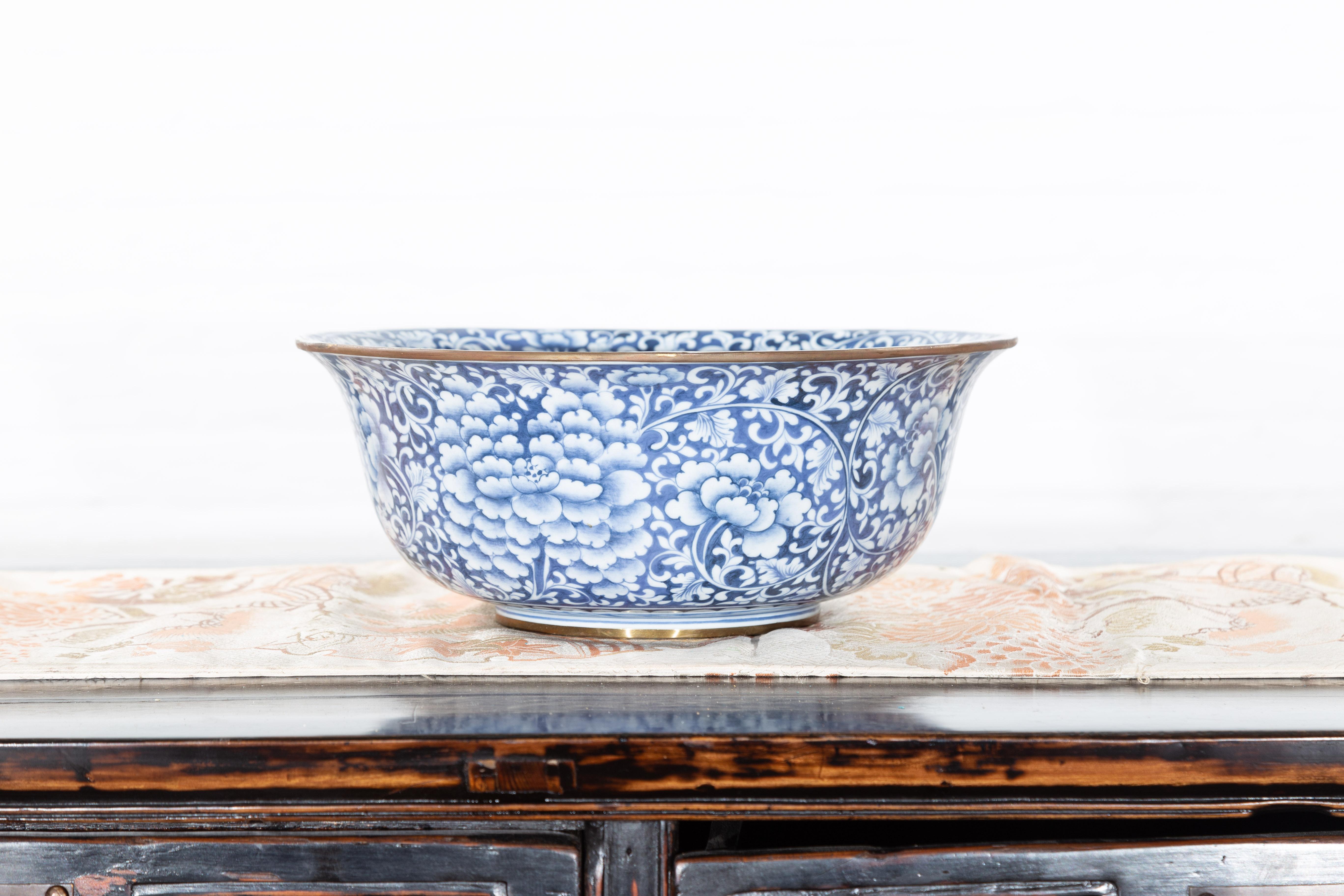 A contemporary Thai hand-painted blue and white porcelain bowl with floral motifs. Created in Thailand, this porcelain bowl features a circular tapering Silhouette with flaring lip, adorned with an abundant blue and white décor made of flowers and