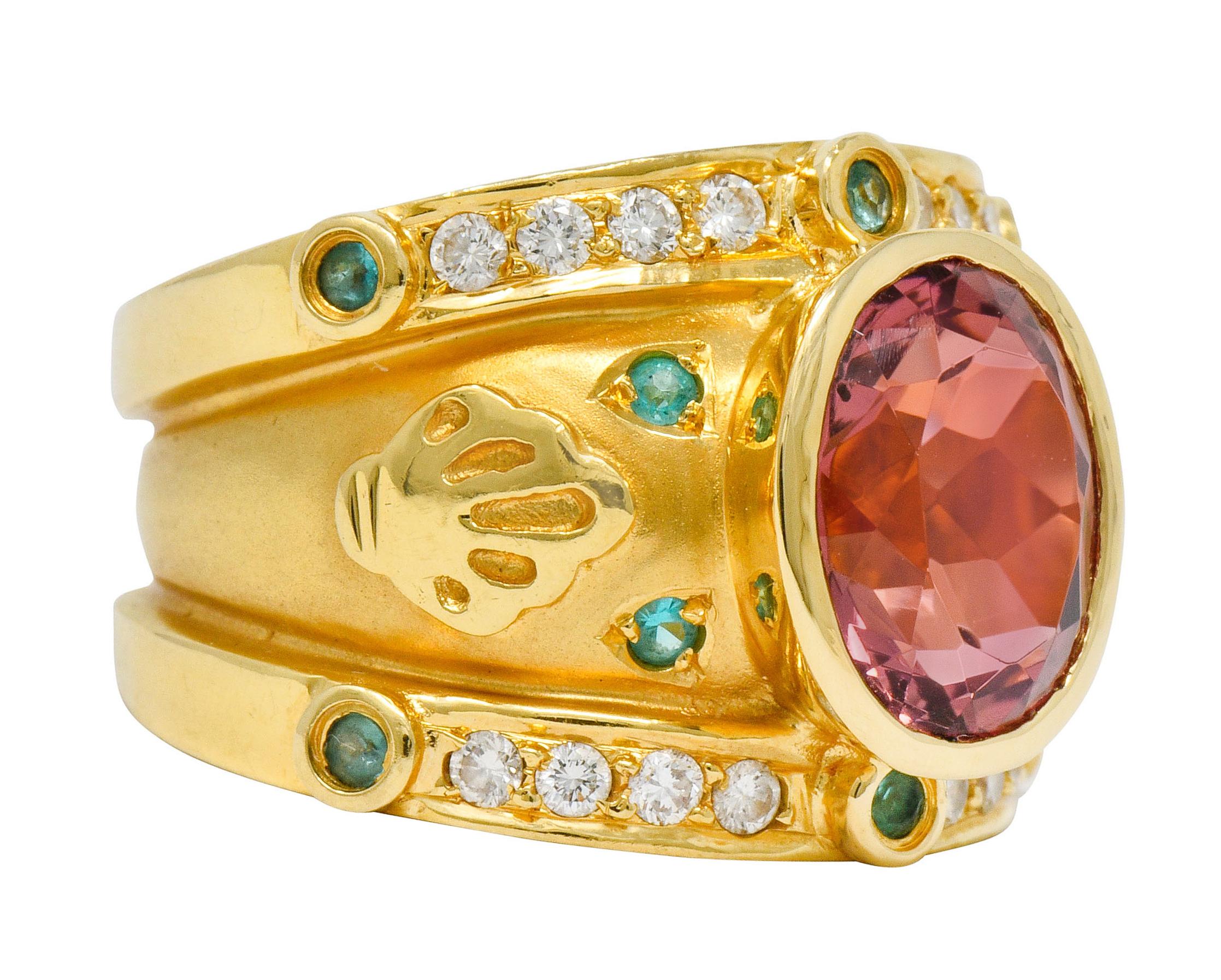 Centering a bezel set oval cut tourmaline measuring approximately 11.0 x 9.0 mm, transparent and orangey-pink in color

Flanked North and South with rows of bead set round brilliant cut diamonds weighing approximately 0.40 carat, eye-clean and