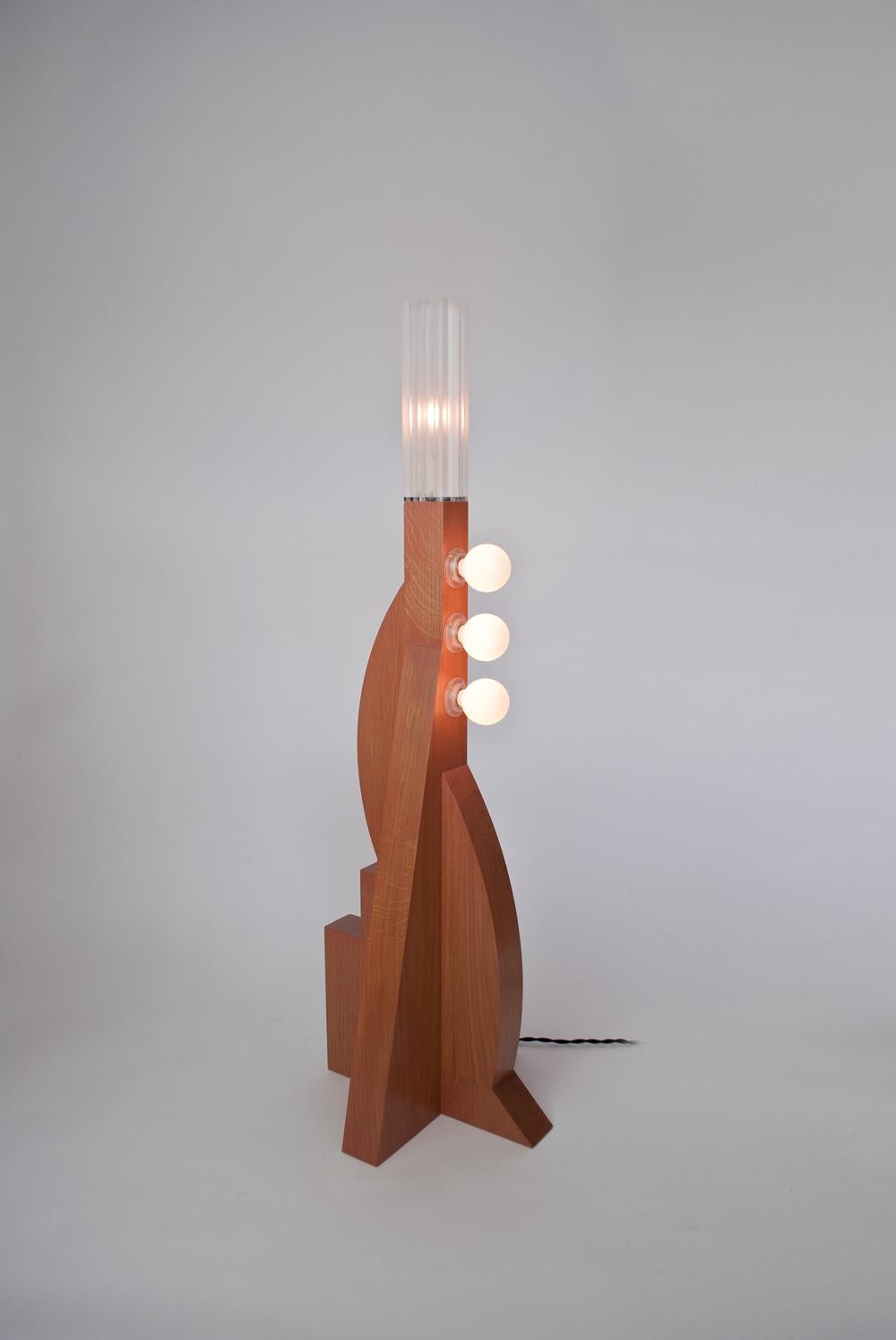 The Tower floor lamp V2 is a One-off design by Louis Jobst. It has an asymmetric solid oak base made up from harmonised geometric forms with a Terracotta finish. The design echoes postmodernist, Memphis design with multiple bulbs and bold shapes and