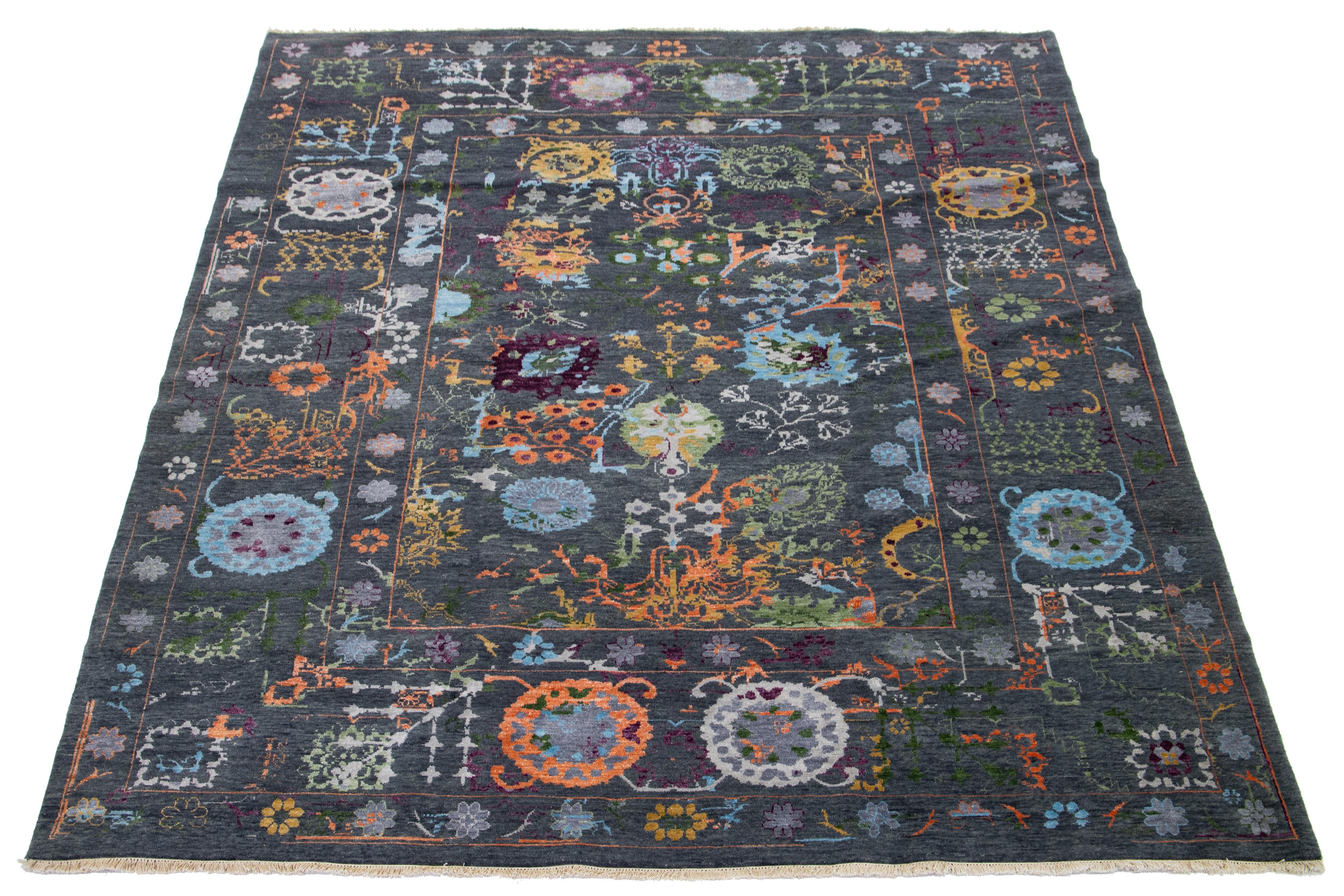 Stunning in its contemporary style, this wool rug showcases a mesmerizing floral design in a captivating shade of gray-charcoal. Its allure is heightened by the exquisitely multicolor accents that effortlessly harmonize with the distinctive floral
