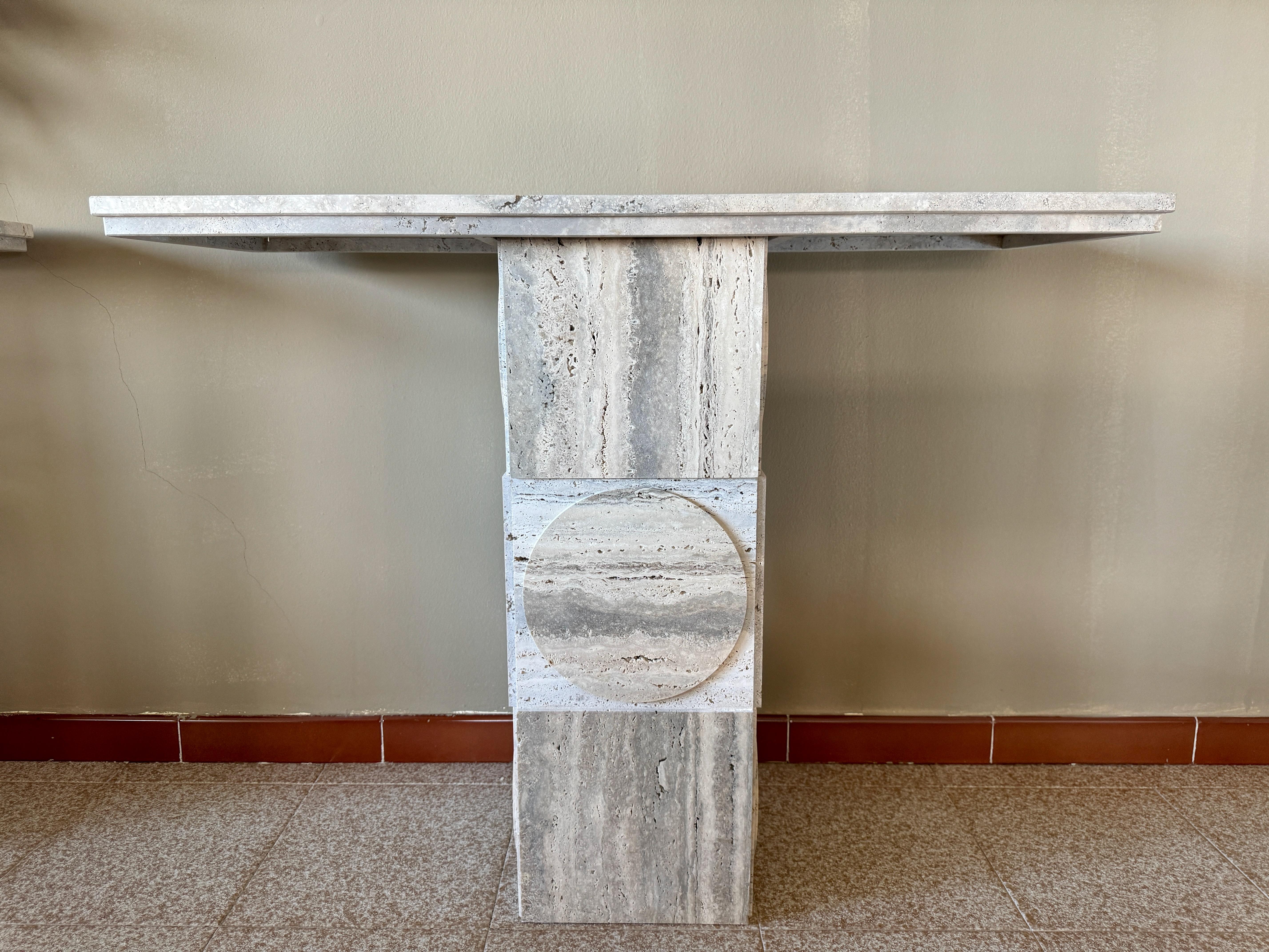 This travertine console table is an elegant piece that showcases the timeless beauty of natural stone. The table is crafted entirely from travertine, featuring a smooth, rectangular top with a strikingly modern aesthetic. The natural variations and