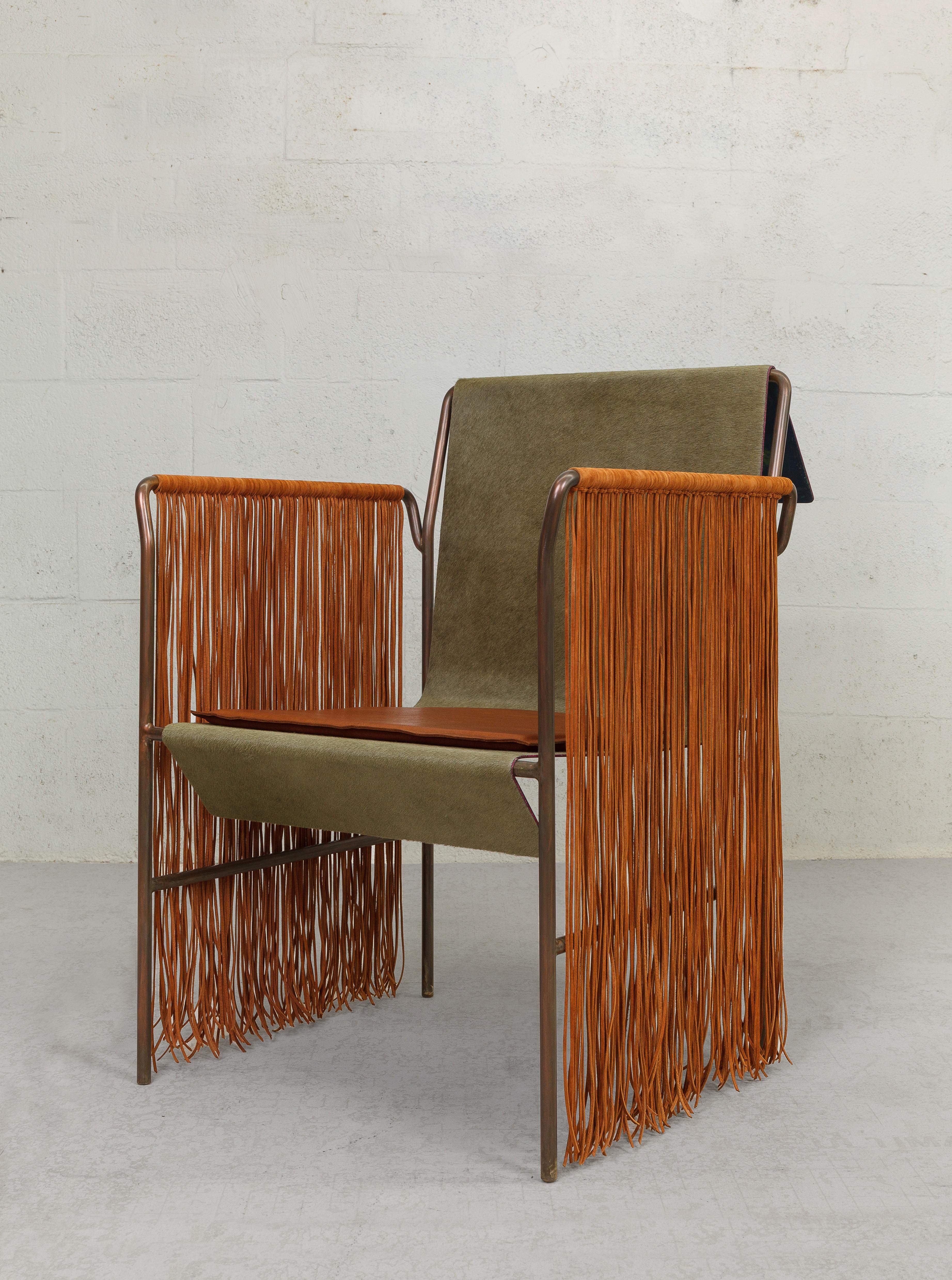 The contemporary Native chair design incorporates materials reminiscent of tribal Indian cultures akin to a modern throne-like chair made from a combination of leather, lace fringe, and hair-on-hide. The chair features a sturdy frame made from solid