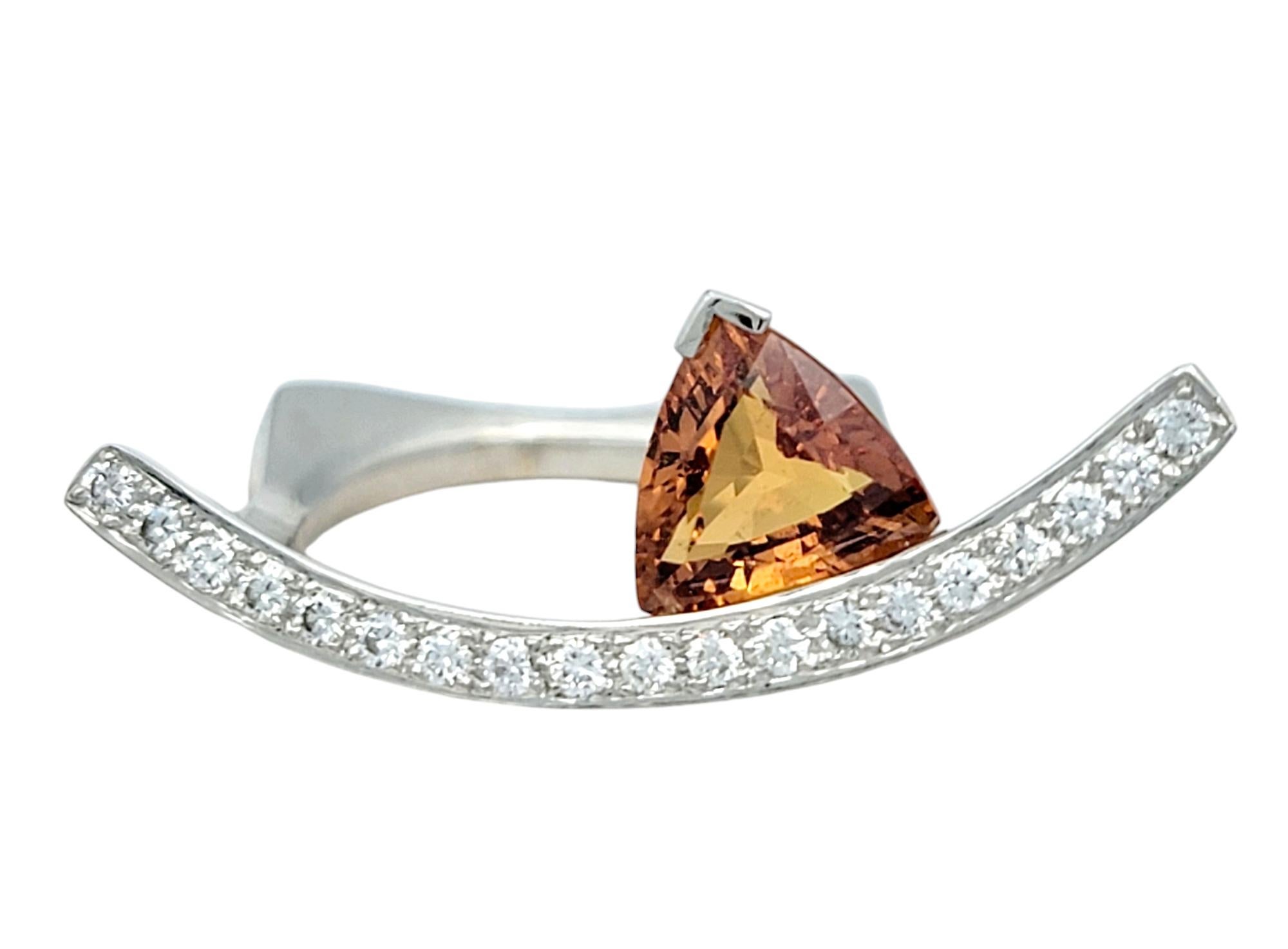 Ring Size: 4 

Ignite your style with this stunning contemporary ring featuring a brilliant trillion-cut spessartite, a gemstone known for its rich, fiery orange hue. Set in 18 karat white gold, the bold spessartite floats gracefully above a curved