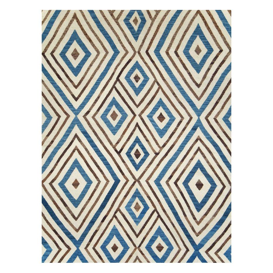 A modern Turkish flatweave Kilim large room size carpet handmade during the 21st century with a contemporary asymmetrical diamond lattice design in blue and brown over a cream background.

Measures: 11' 3