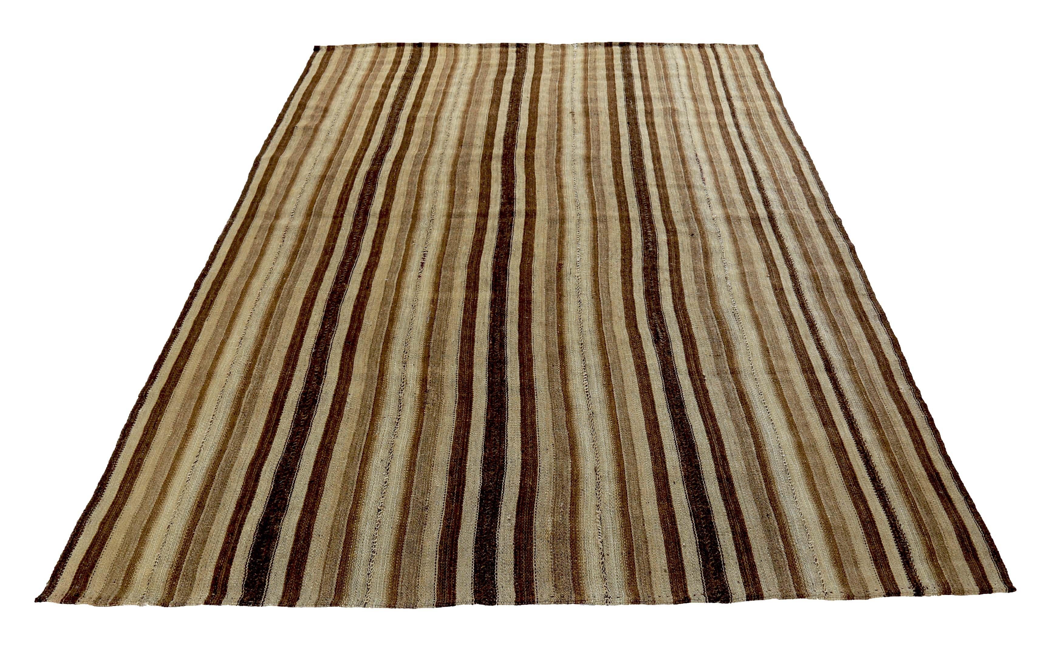Contemporary Turkish rug handwoven from the finest sheep’s wool and colored with all-natural vegetable dyes that are safe for humans and pets. It’s a traditional Kilim flat-weave design featuring black and brown stripes on a beige field. It’s a