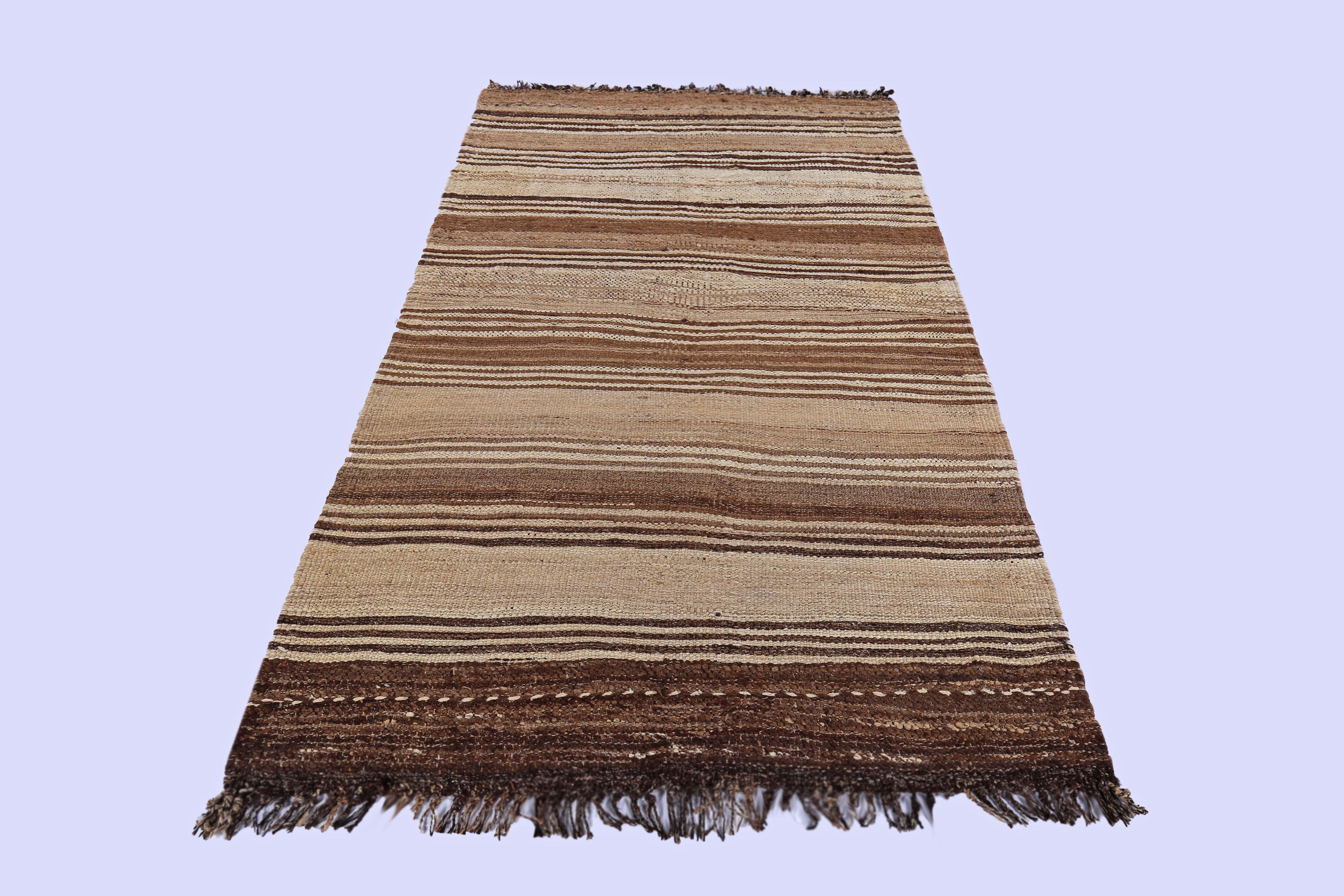 Contemporary Turkish rug handwoven from the finest sheep’s wool and colored with all-natural vegetable dyes that are safe for humans and pets. It’s a traditional Kilim flat-weave design featuring brown stripes on a beige field. It’s a stunning piece