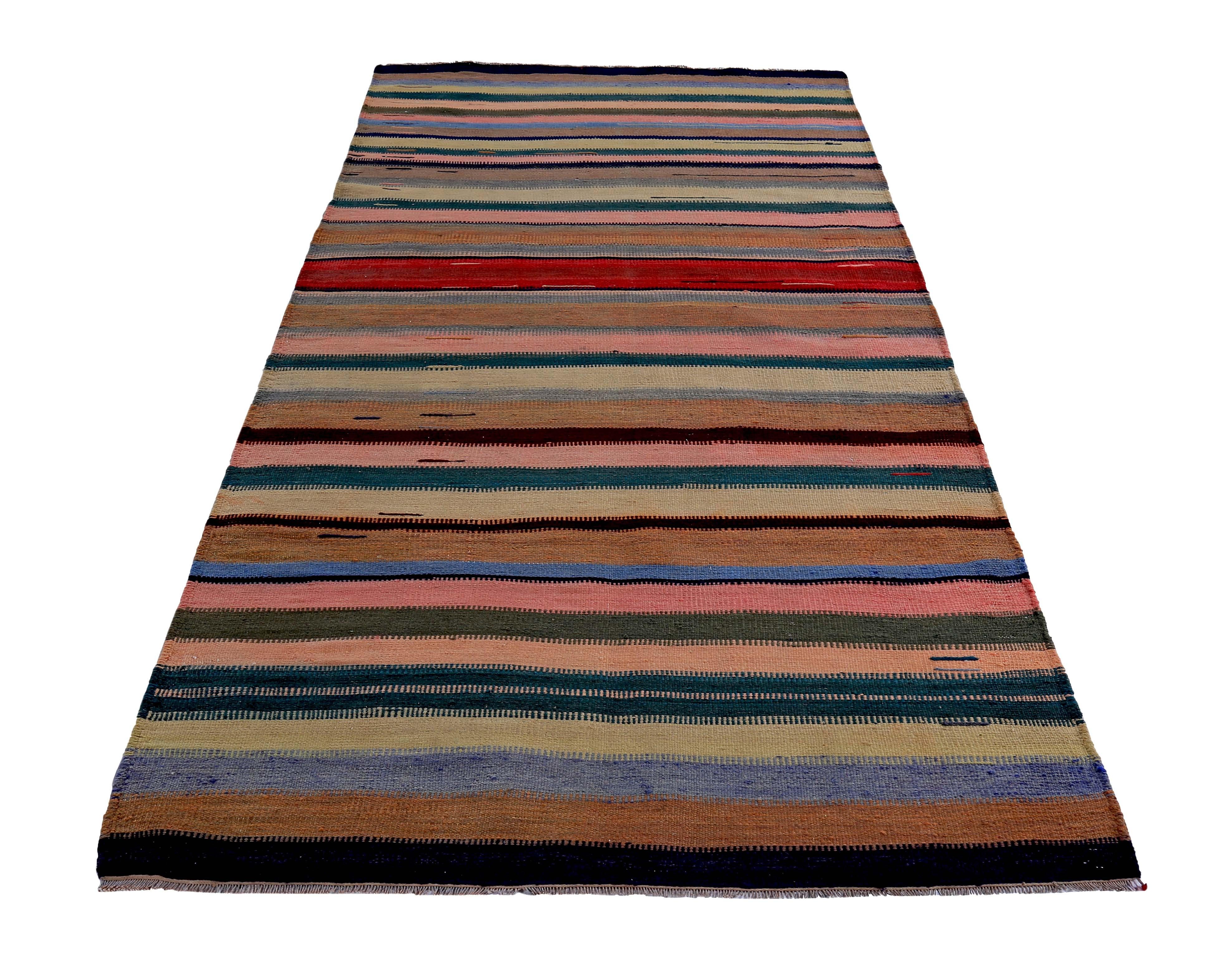 Contemporary Turkish rug handwoven from the finest sheep’s wool and colored with all-natural vegetable dyes that are safe for humans and pets. It’s a traditional Kilim flat-weave design featuring green, red and pink stripes on a black field. It’s a