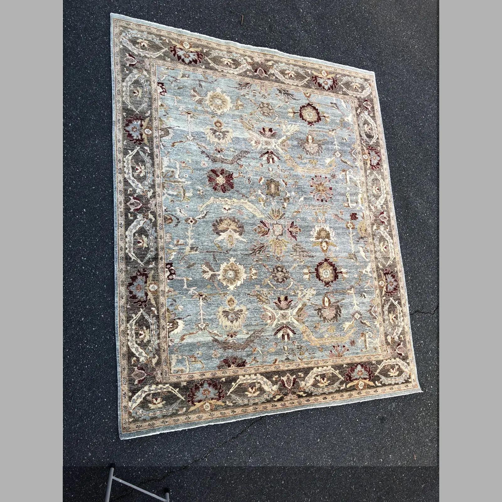Contemporary Turkish Oushak wool woven rug with a stunning botanical print design. Vibrant blend/ombre of light blues in the center with sand colored perimeter and pink/maroon accents throughout. Hand-knotted, this rug features a lovely blend of