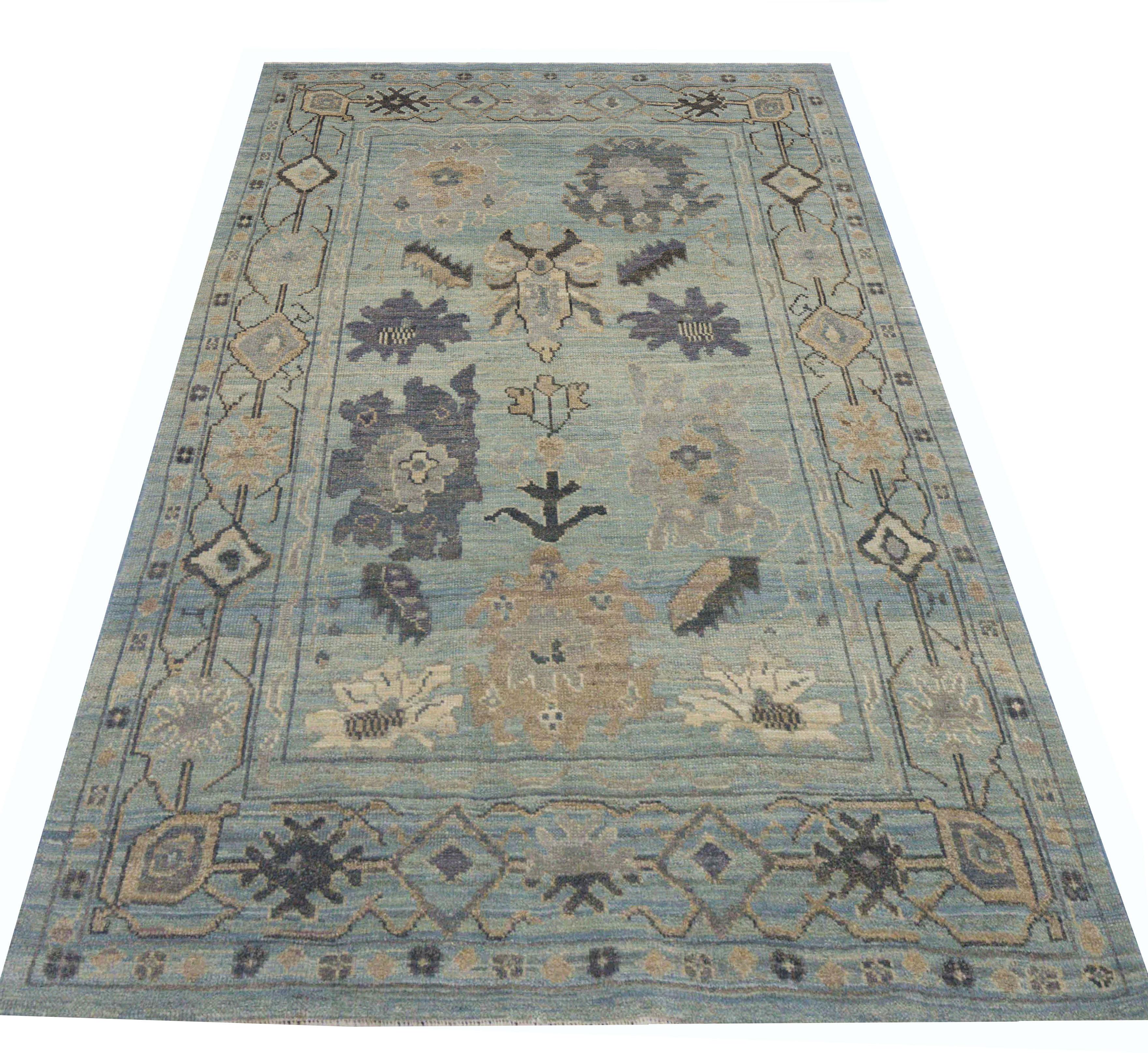  Contemporary Turkish rug made of handwoven sheep’s wool of the finest quality. It’s colored with organic vegetable dyes that are certified safe for humans and pets alike. It features a blend of beige and blue field with flower medallions in gray
