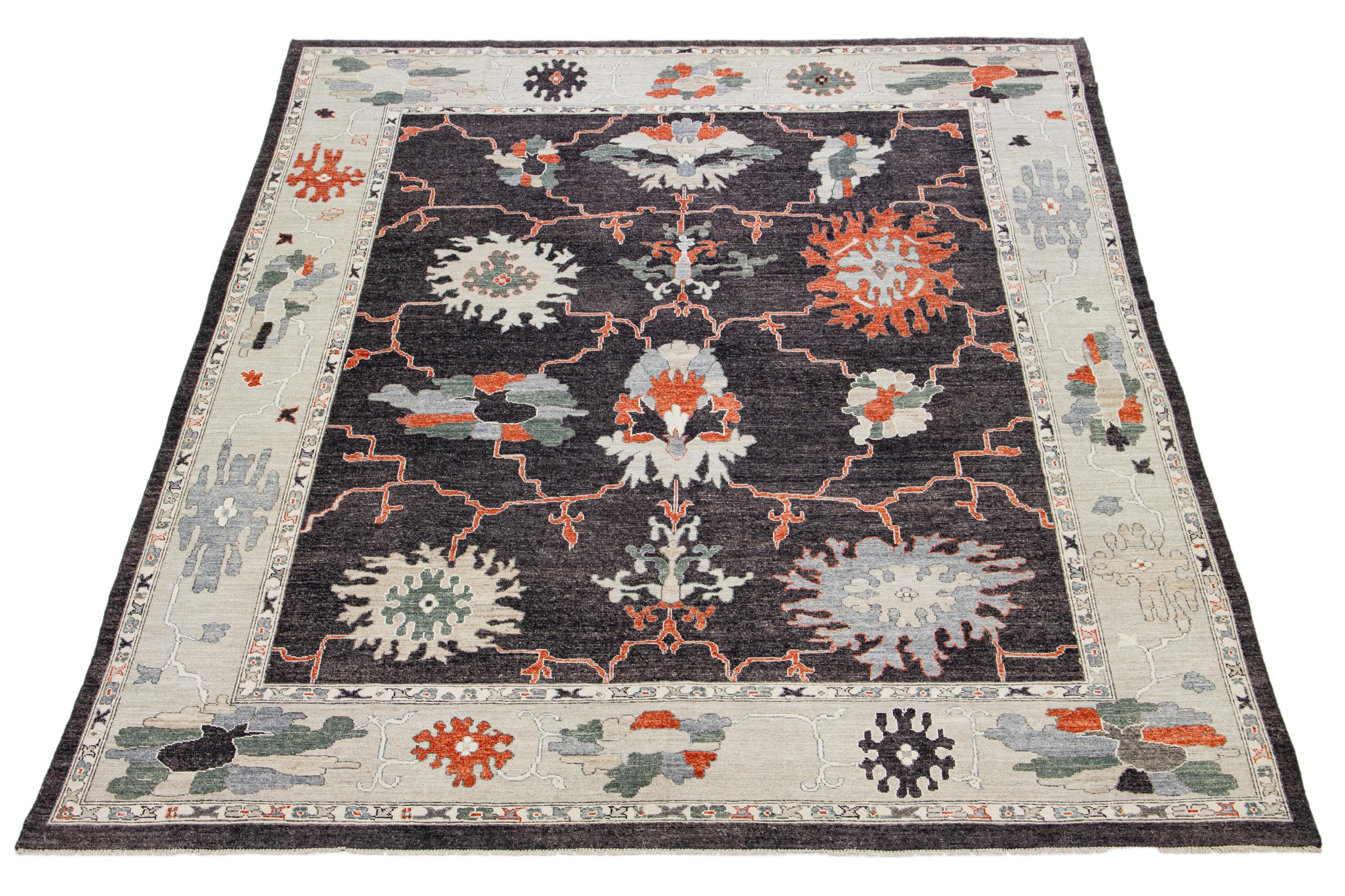 This oversized wool rug boasts a charming gray charcoal base and captivating floral pattern with stunning orange, gray, and green accents. It's hand-knotted with utmost attention to detail and will complement any decor.

This rug measures 11'11