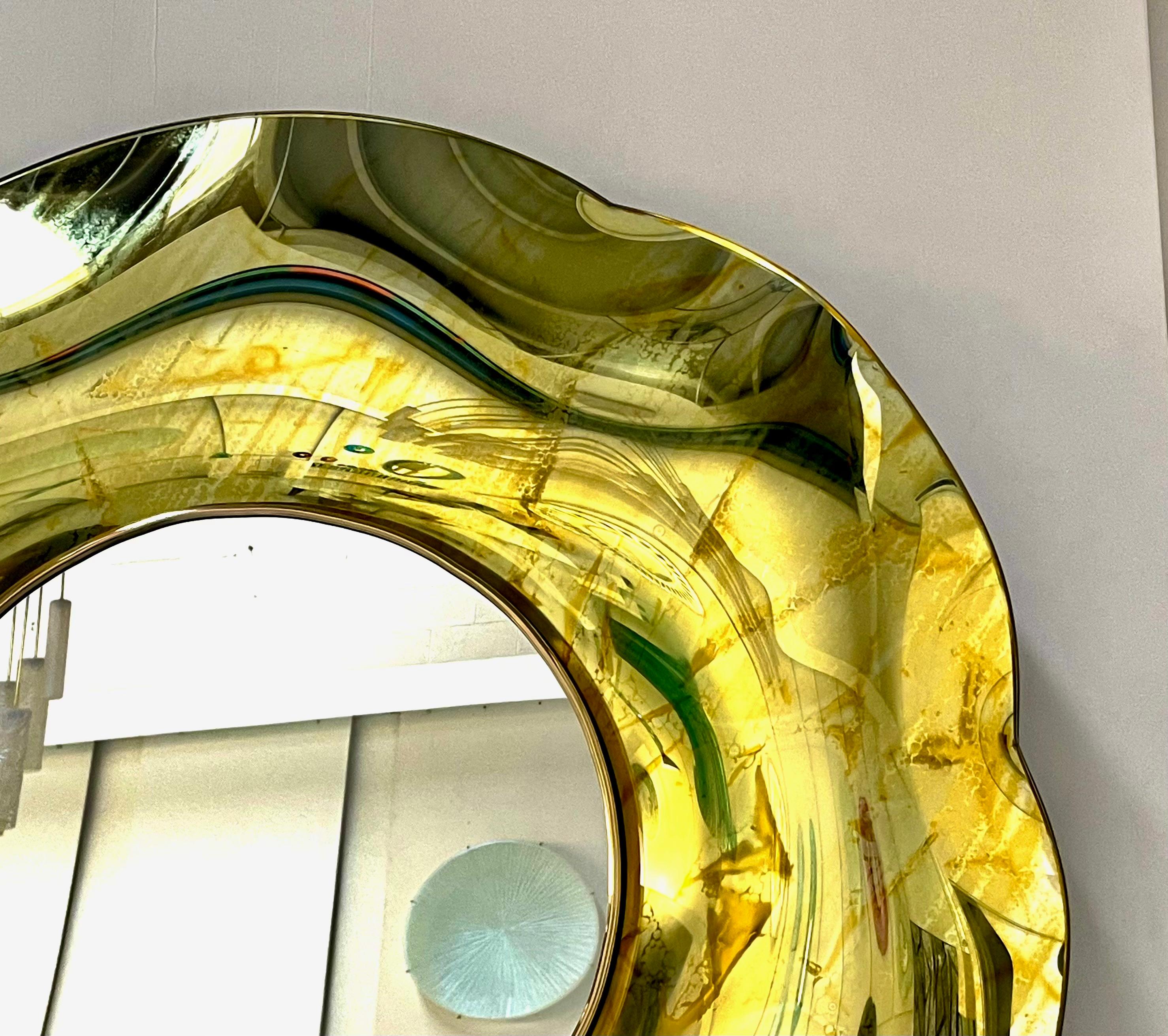 Der gewellte Spiegel 'Undulate' ist ein Kunstobjekt aus reiner Kunst und italienischem Design. 
Das Kristall wurde vom Künstler handgefertigt und fachmännisch gebogen. 
Die Trägerstruktur besteht aus Holz und Messing. 
Seine runde Form und seine